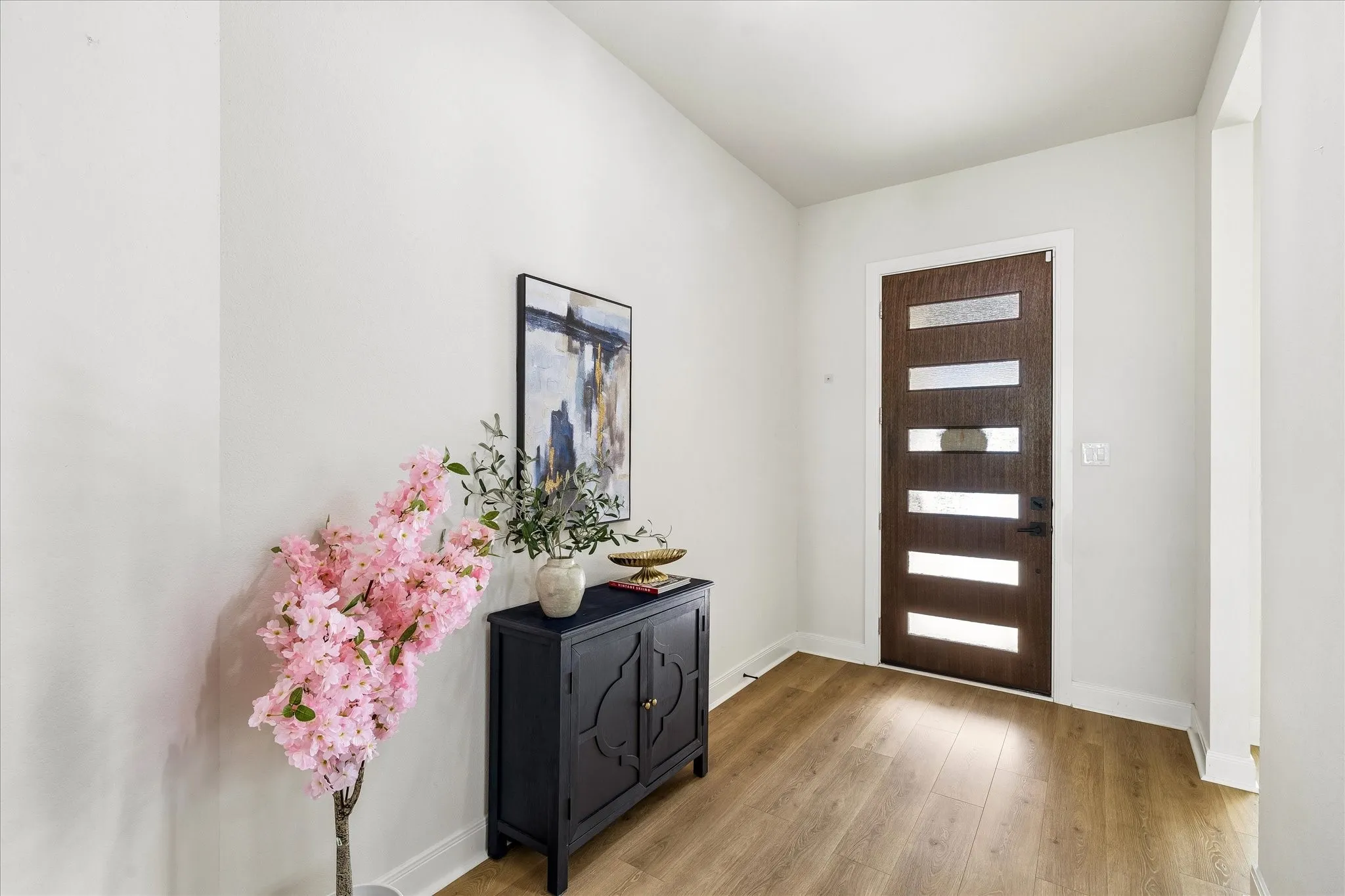 Entryway featuring wood-finish flooring and a contemporary dark wood entry door with horizontal frosted glass panes