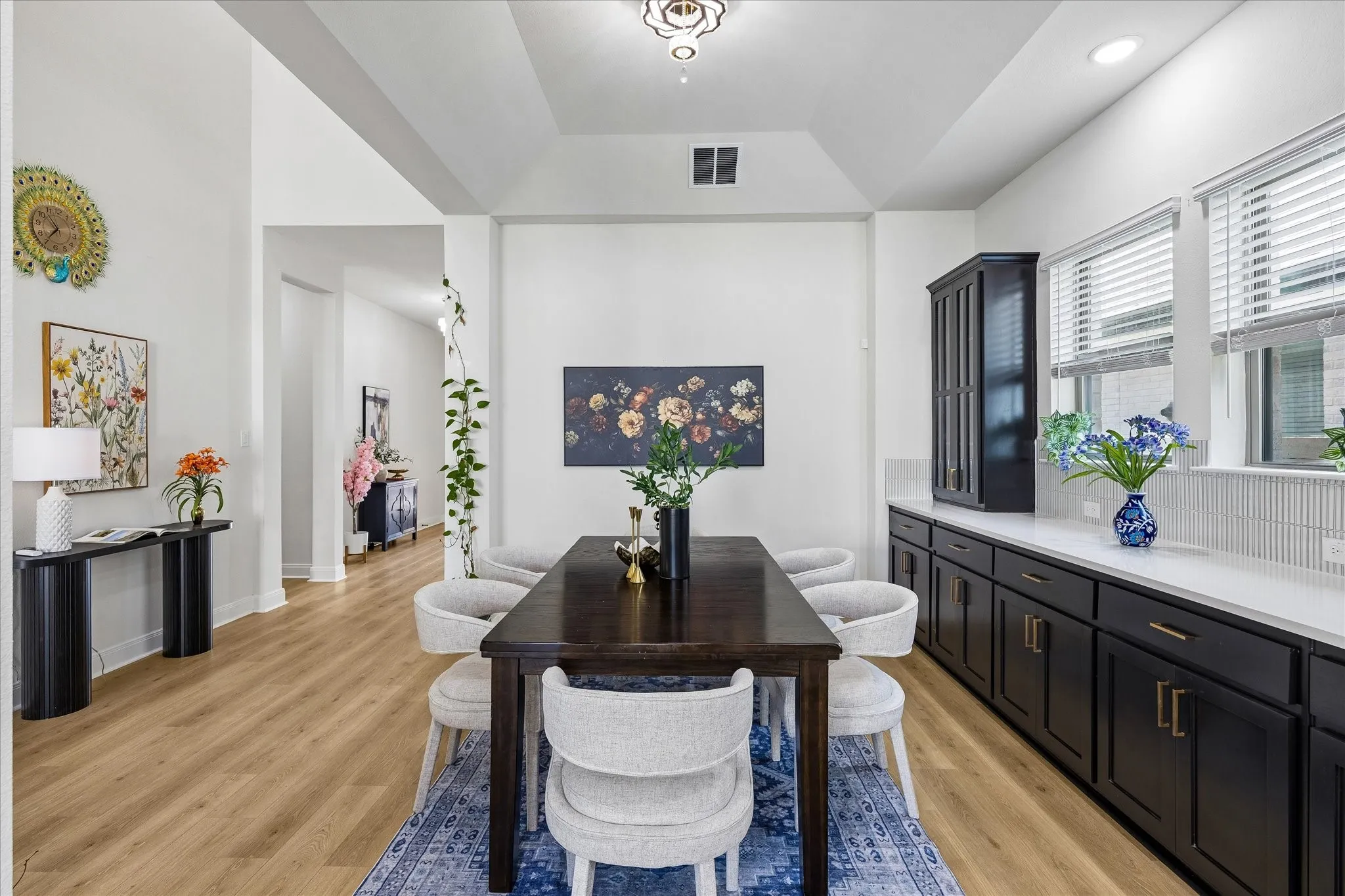 Dining area featuring wood-finish flooring, a recessed ceiling with decorative lighting, and a built-in buffet with dark cabinetry and light countertops