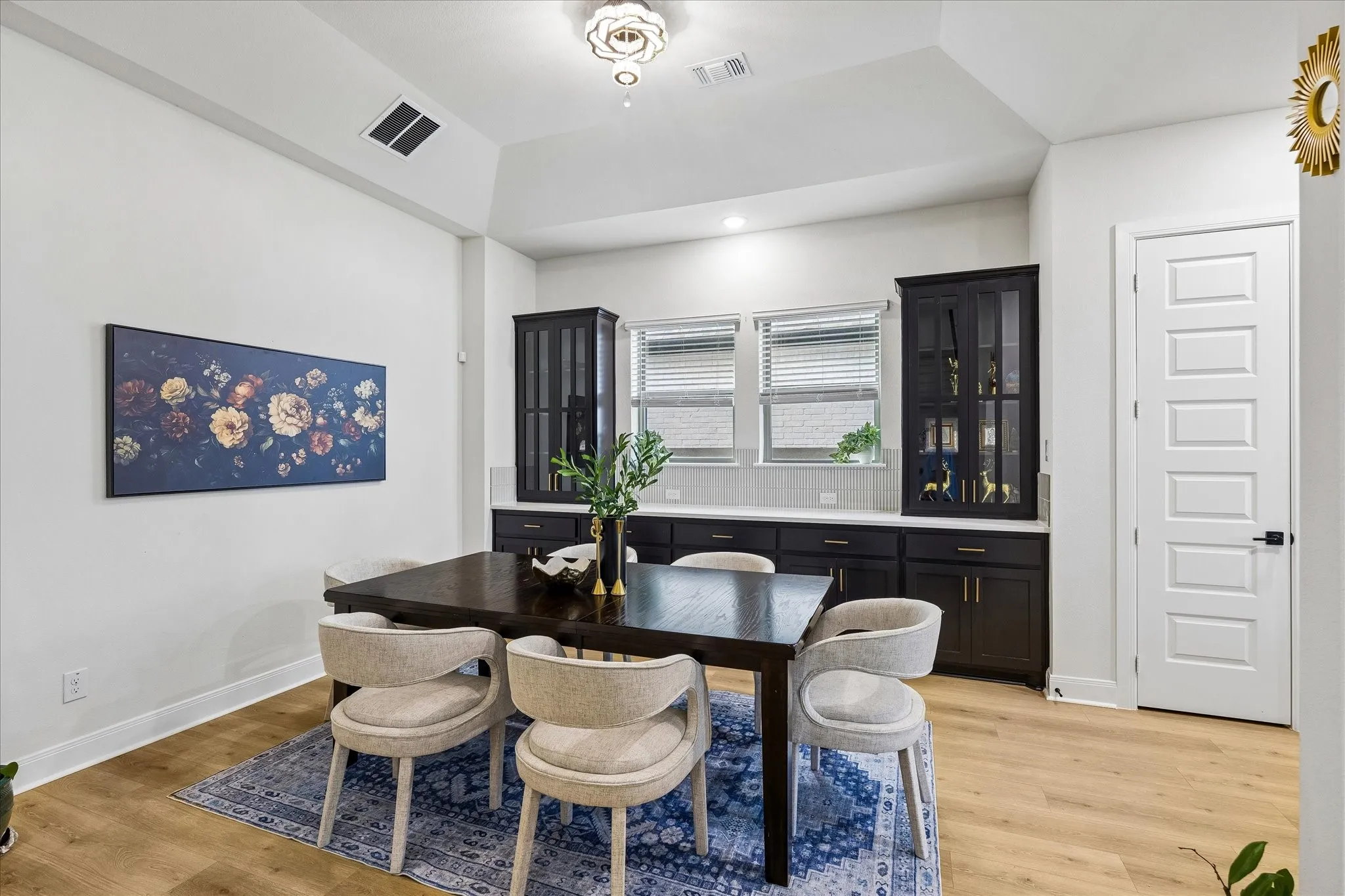Dining area featuring wood-finish flooring and a tray ceiling with a contemporary light fixture
