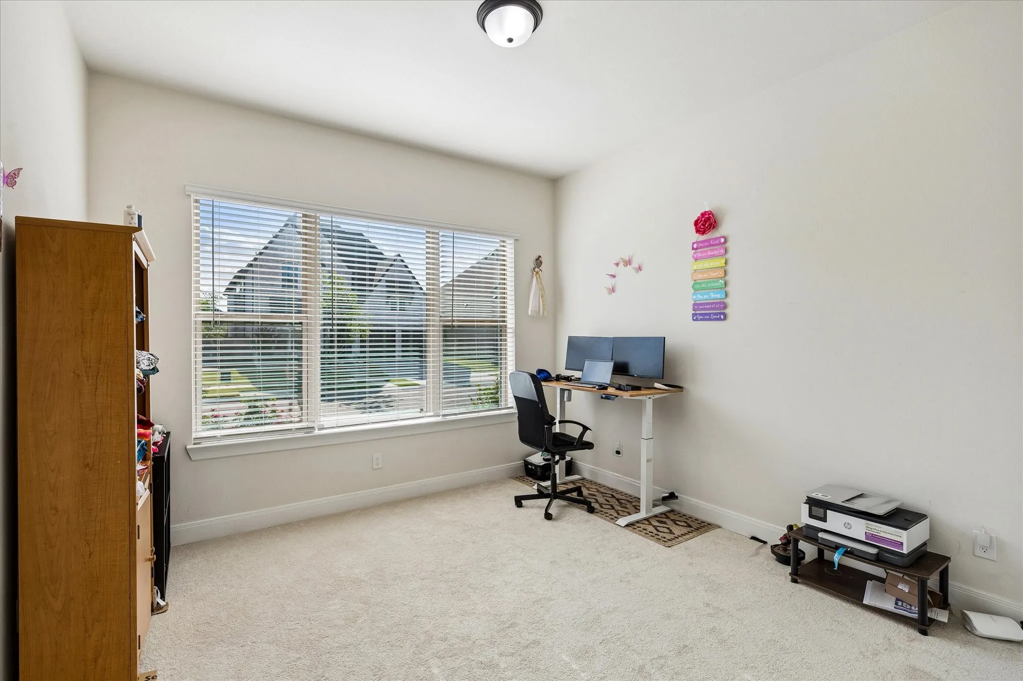 Bright room featuring a large window with horizontal blinds, neutral wall tones, and light-colored carpeting