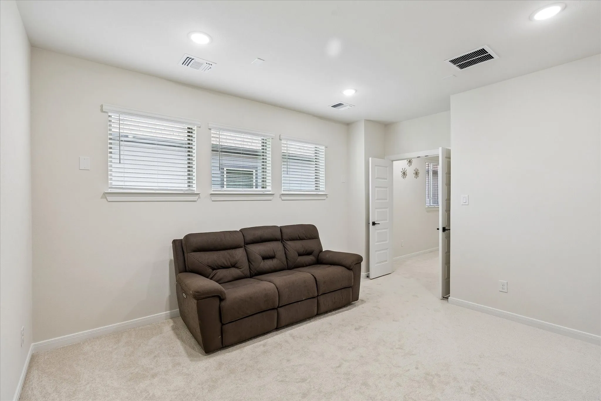 Carpeted room with recessed lighting and three windows featuring white blinds