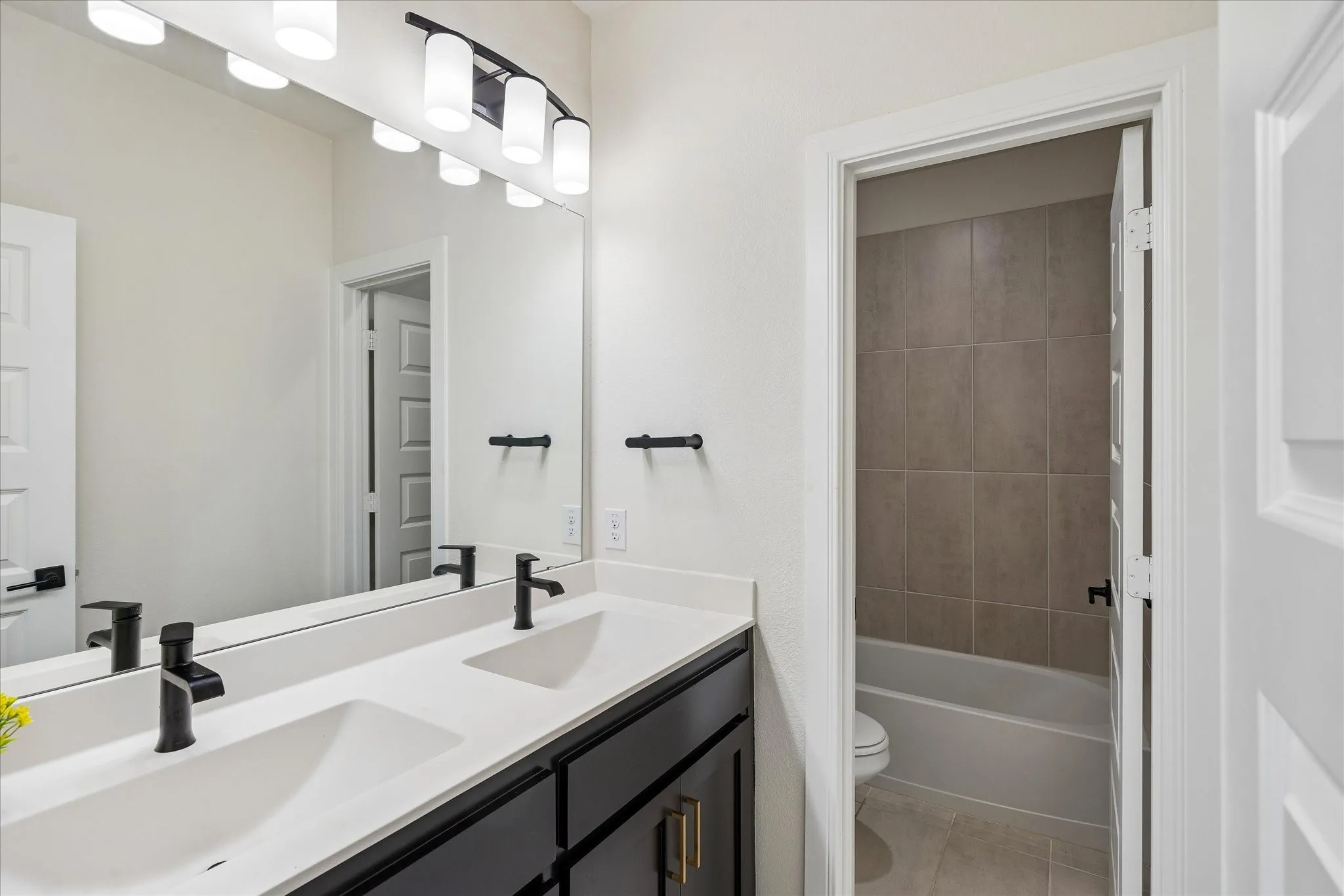 Bathroom featuring a dual vanity with flat-panel cabinetry, white countertops, and matte black fixtures