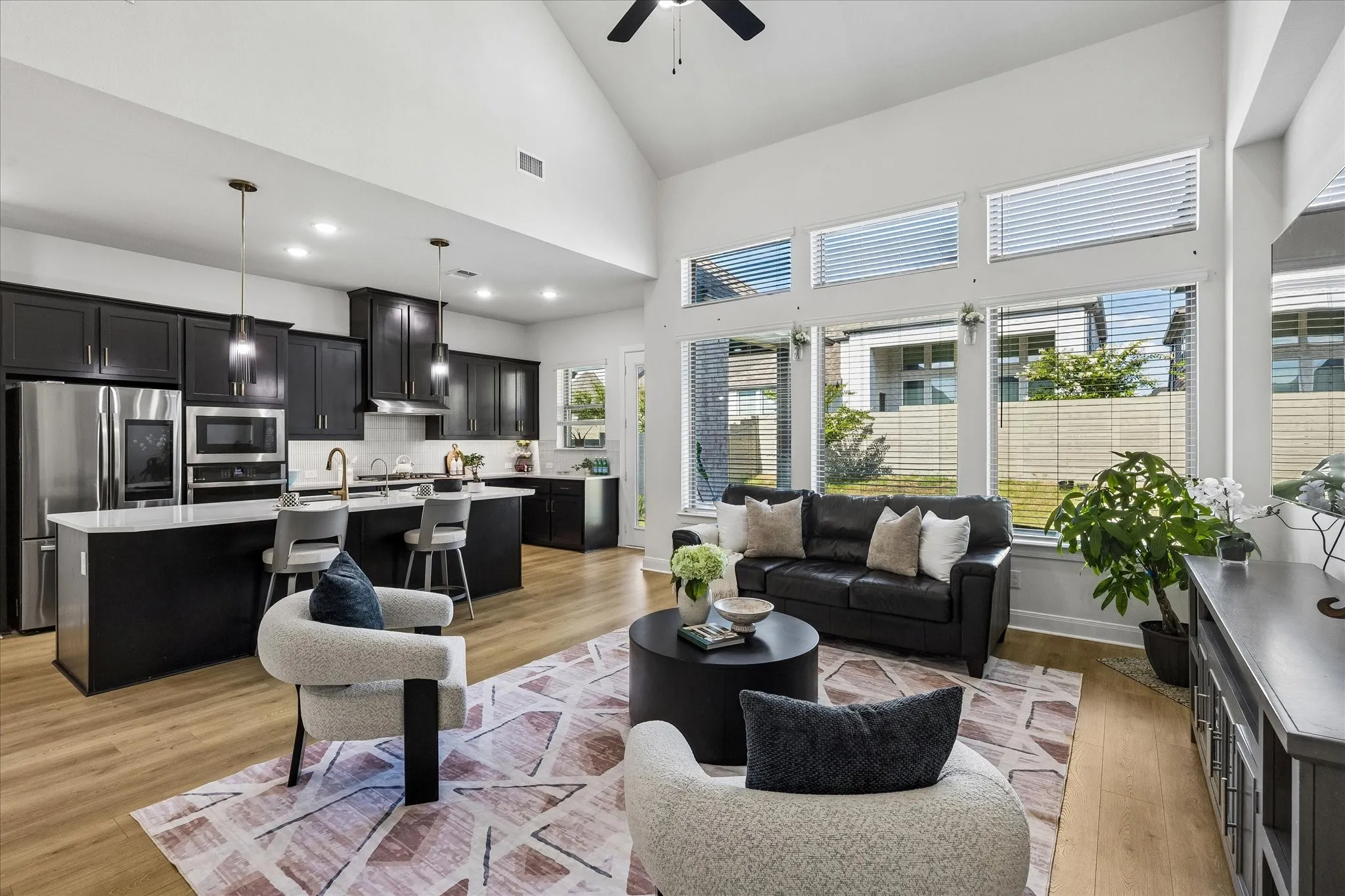 Vaulted ceiling living area featuring wood-finish flooring and a wall of windows