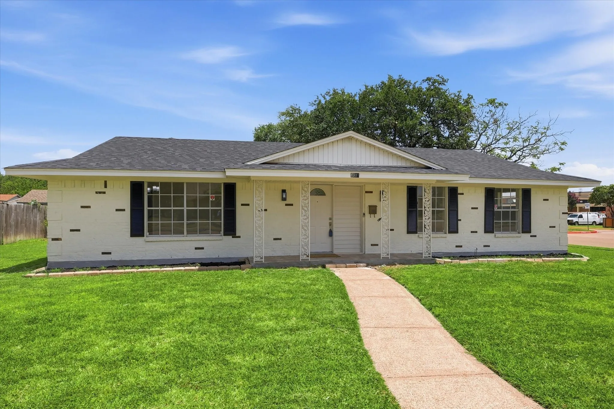 Single-story residence featuring a white brick exterior with dark accent bricks, a dark shingle roof, and a front gabled entry