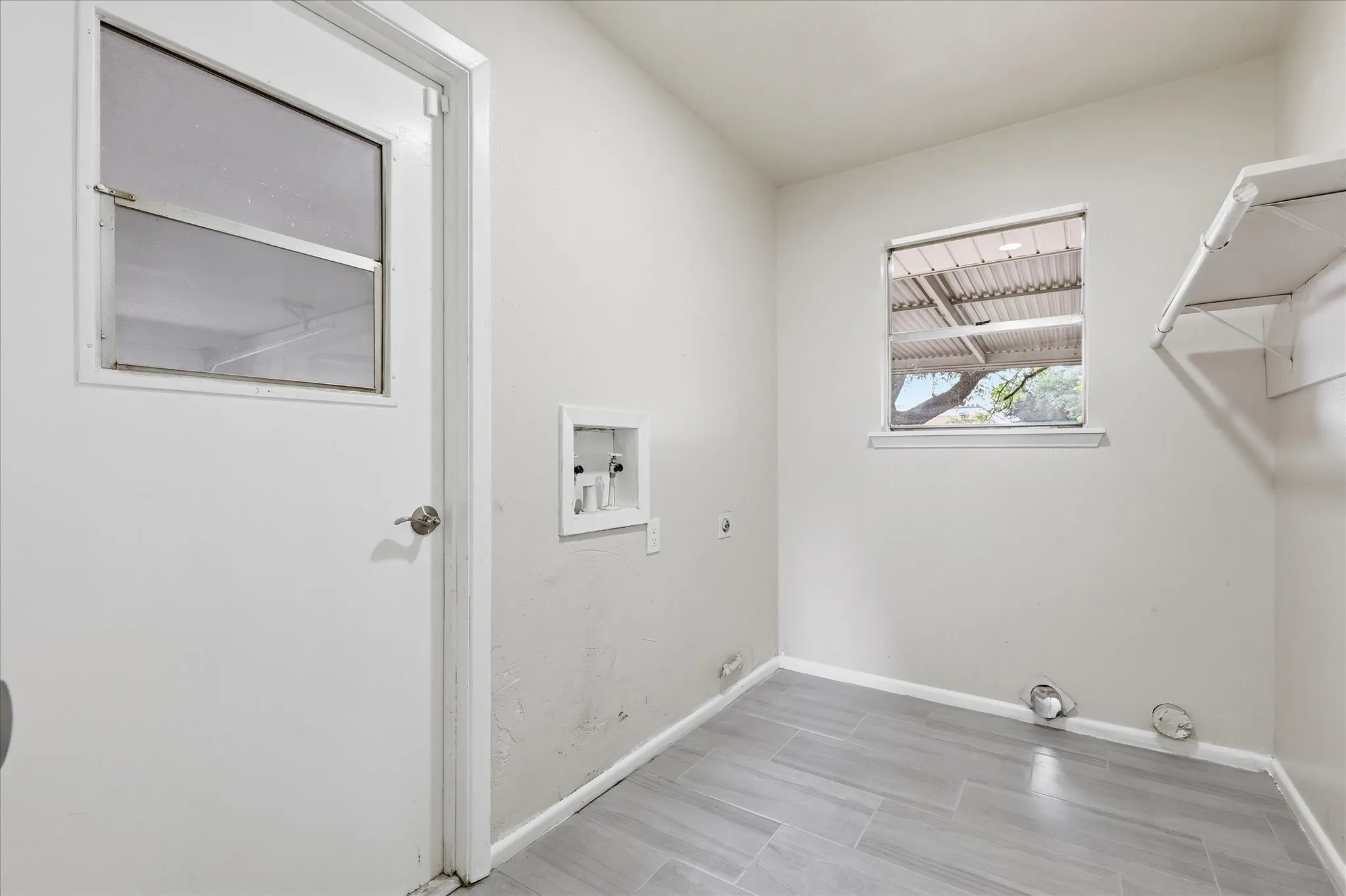 Utility room with wood-finish tile flooring, a window offering natural light, and built-in shelving