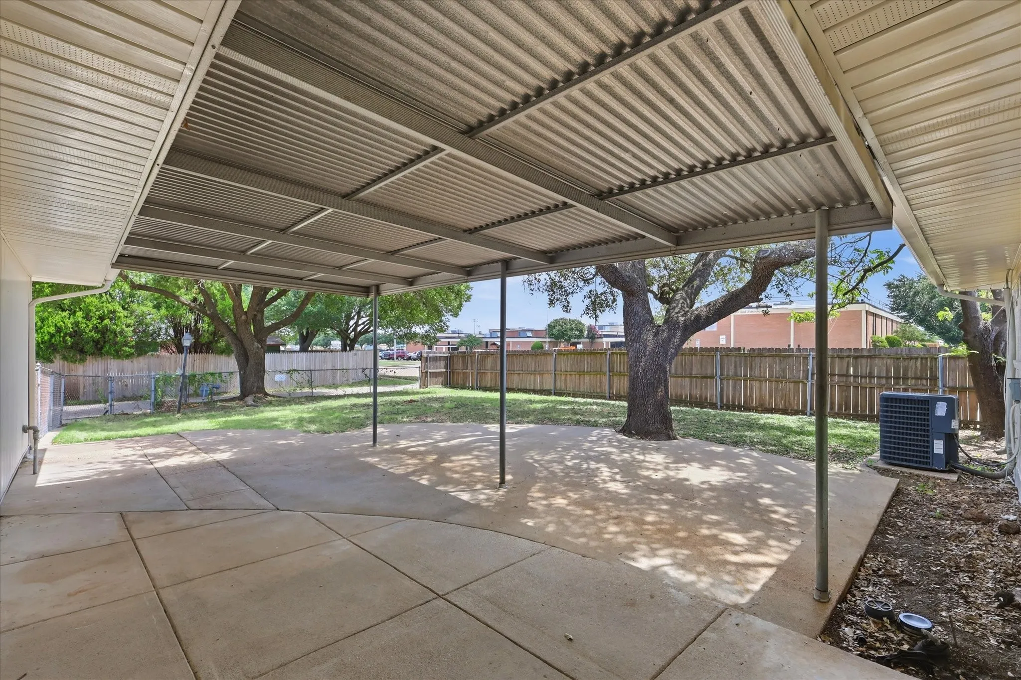 Expansive concrete patio with a full-length metal awning
