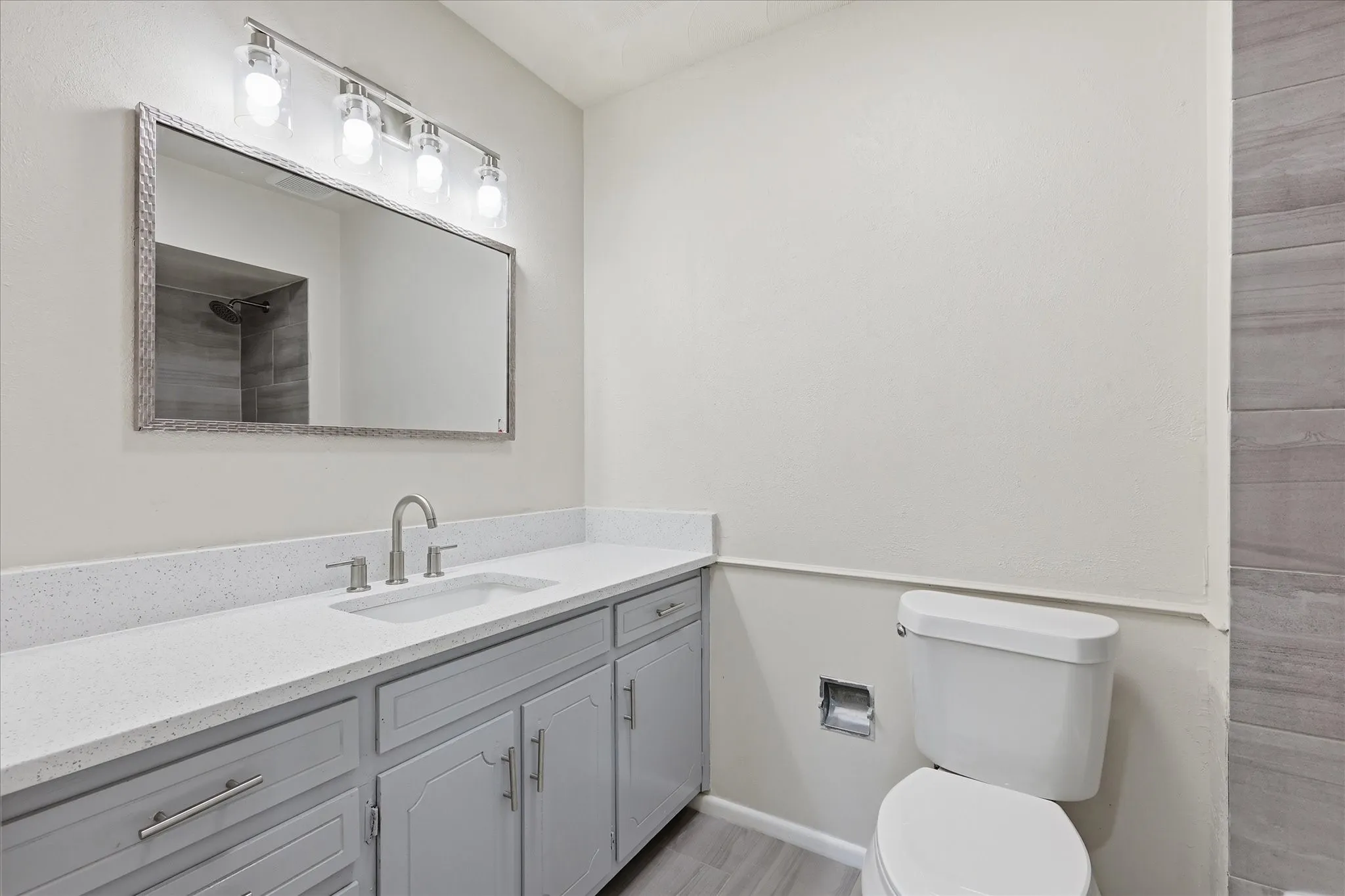 Bathroom vanity featuring a light quartz countertop, undermount sink, and brushed nickel fixtures
