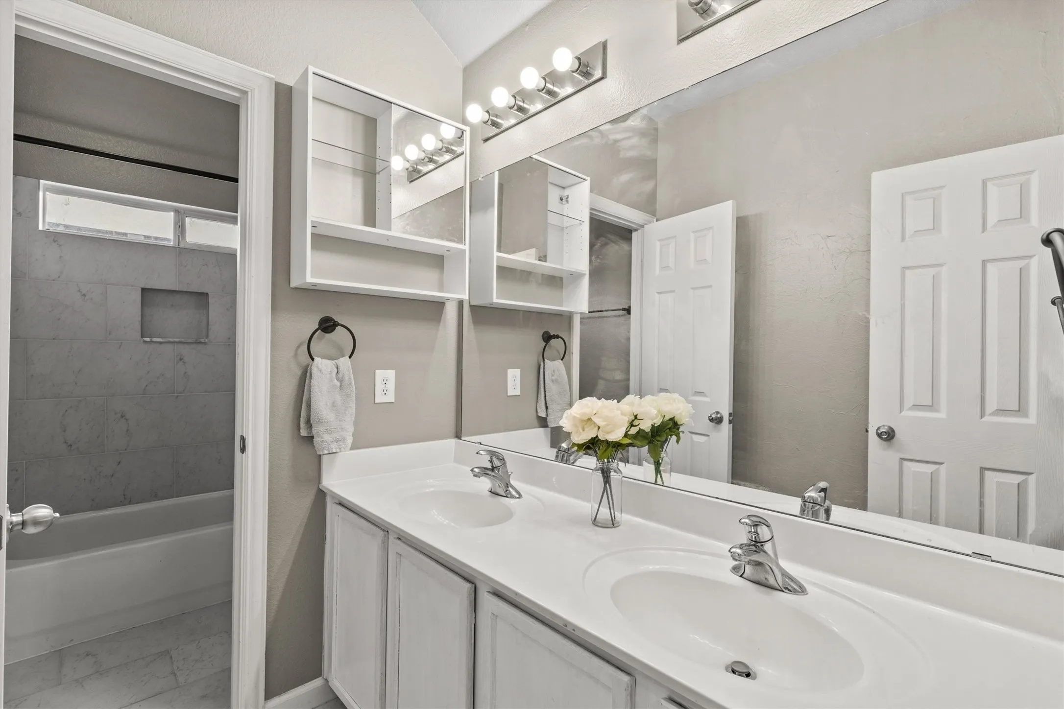 Bathroom vanity featuring dual undermount sinks with chrome faucets, a full-width mirror, and overhead vanity lighting