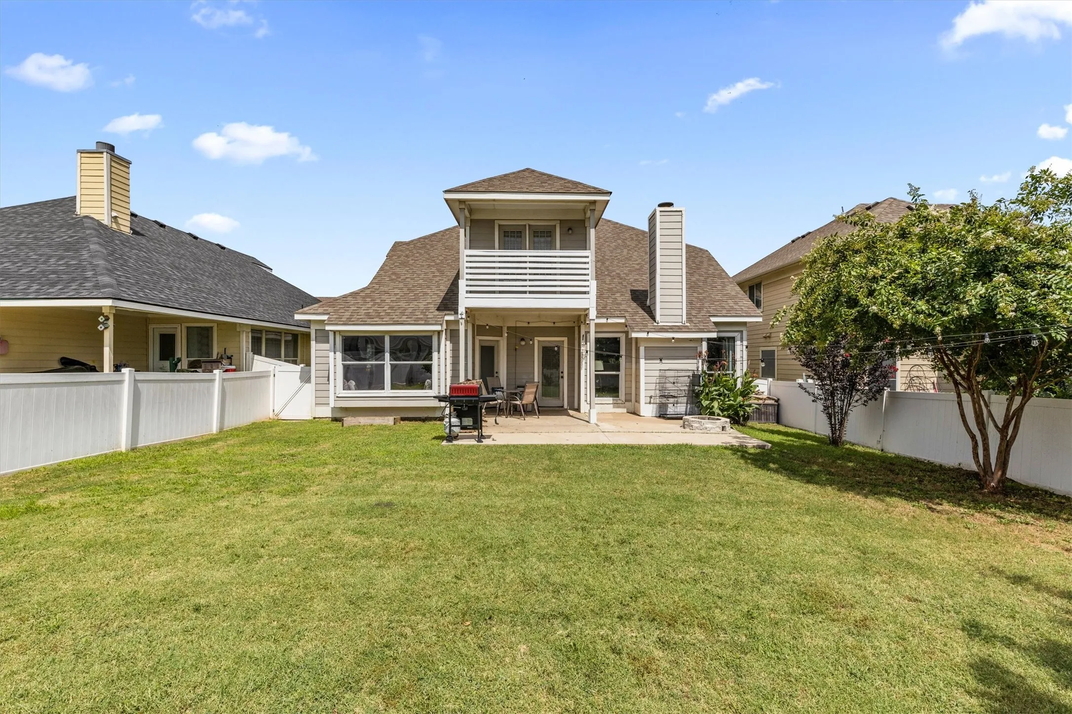 Expansive backyard featuring a manicured lawn, full privacy fencing, and a oversized patio