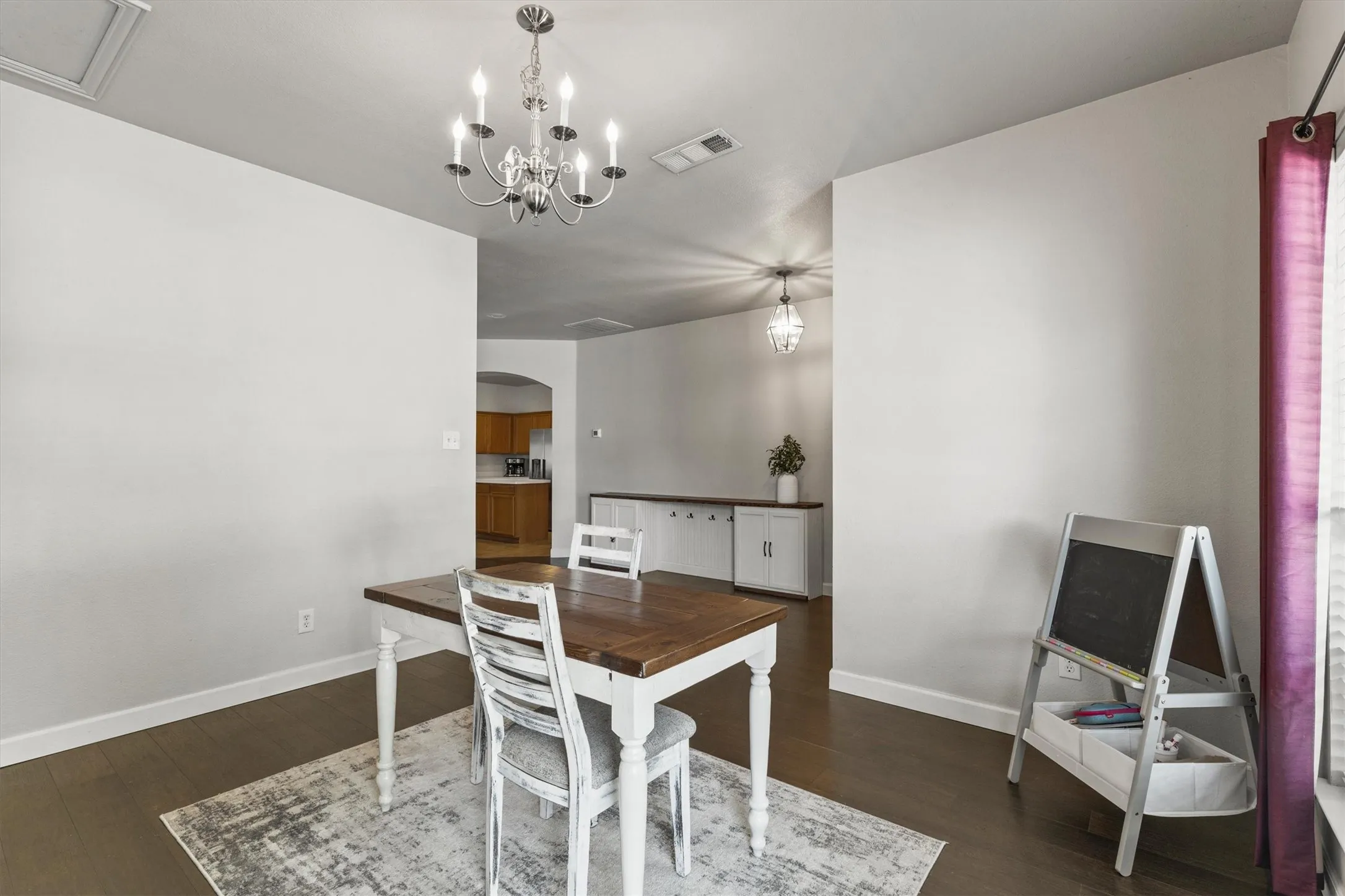 Dining area featuring dark wood-finish flooring, white baseboards, and a brushed nickel chandelier