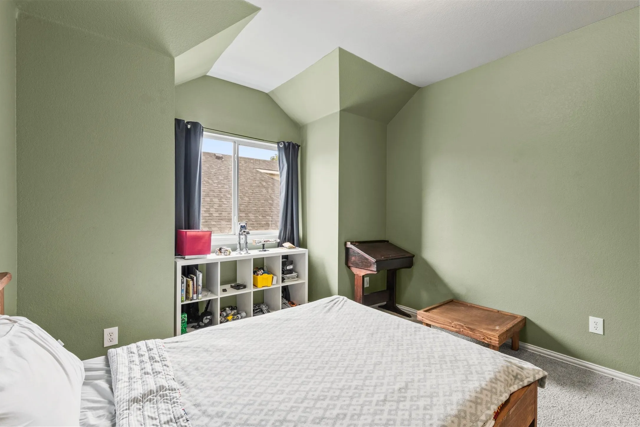 Room featuring light green walls, a vaulted ceiling, and carpet flooring