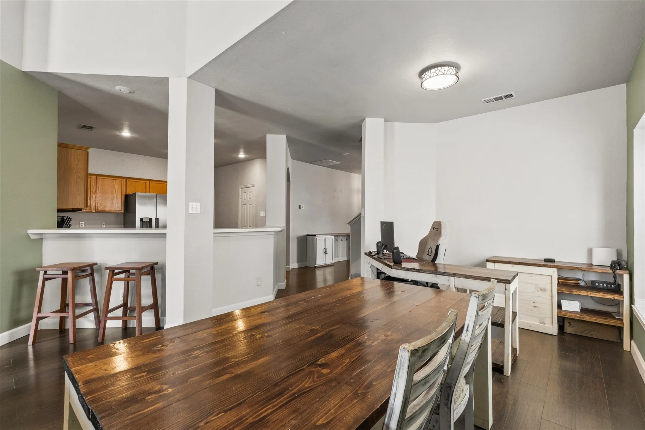 Open concept living area featuring dark wood-finish flooring, a kitchen bar with recessed lighting, and a contemporary ceiling fixture