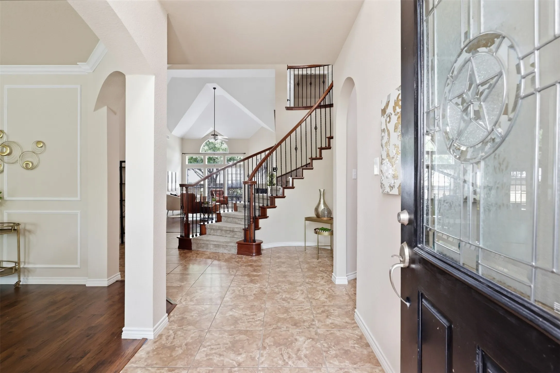 Entryway featuring decorative leaded glass door, tile flooring, and a curved staircase with wrought iron balusters.