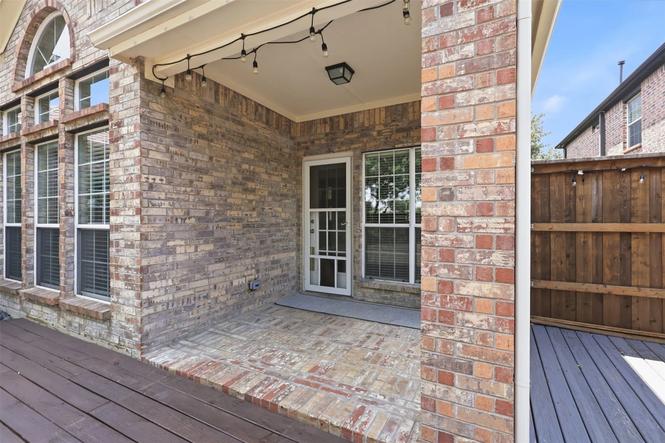Covered patio featuring brick flooring and screen door for natural light.