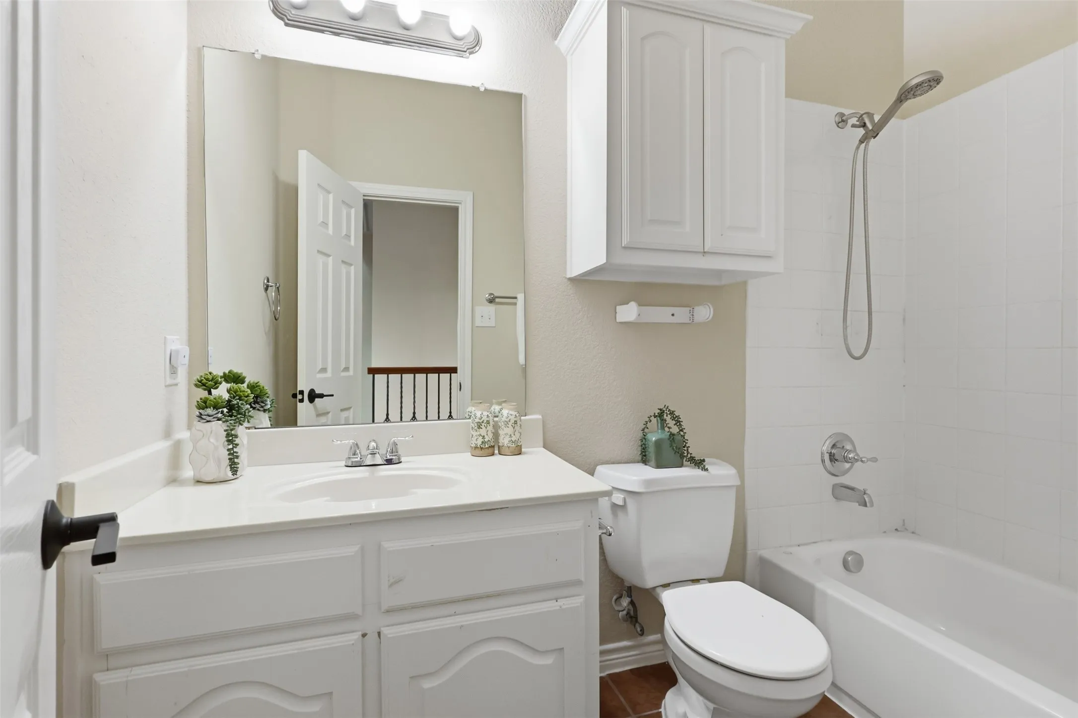 Bathroom featuring a white vanity with an integrated sink and chrome fixtures, a full-width mirror, and a built-in shower-tub combination with white subway tile surround.