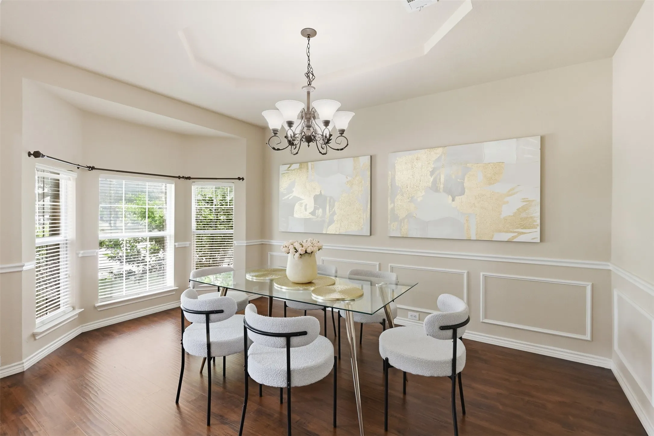 Formal dining area featuring laminate flooring, a decorative chandelier, and wainscoting with panel molding.