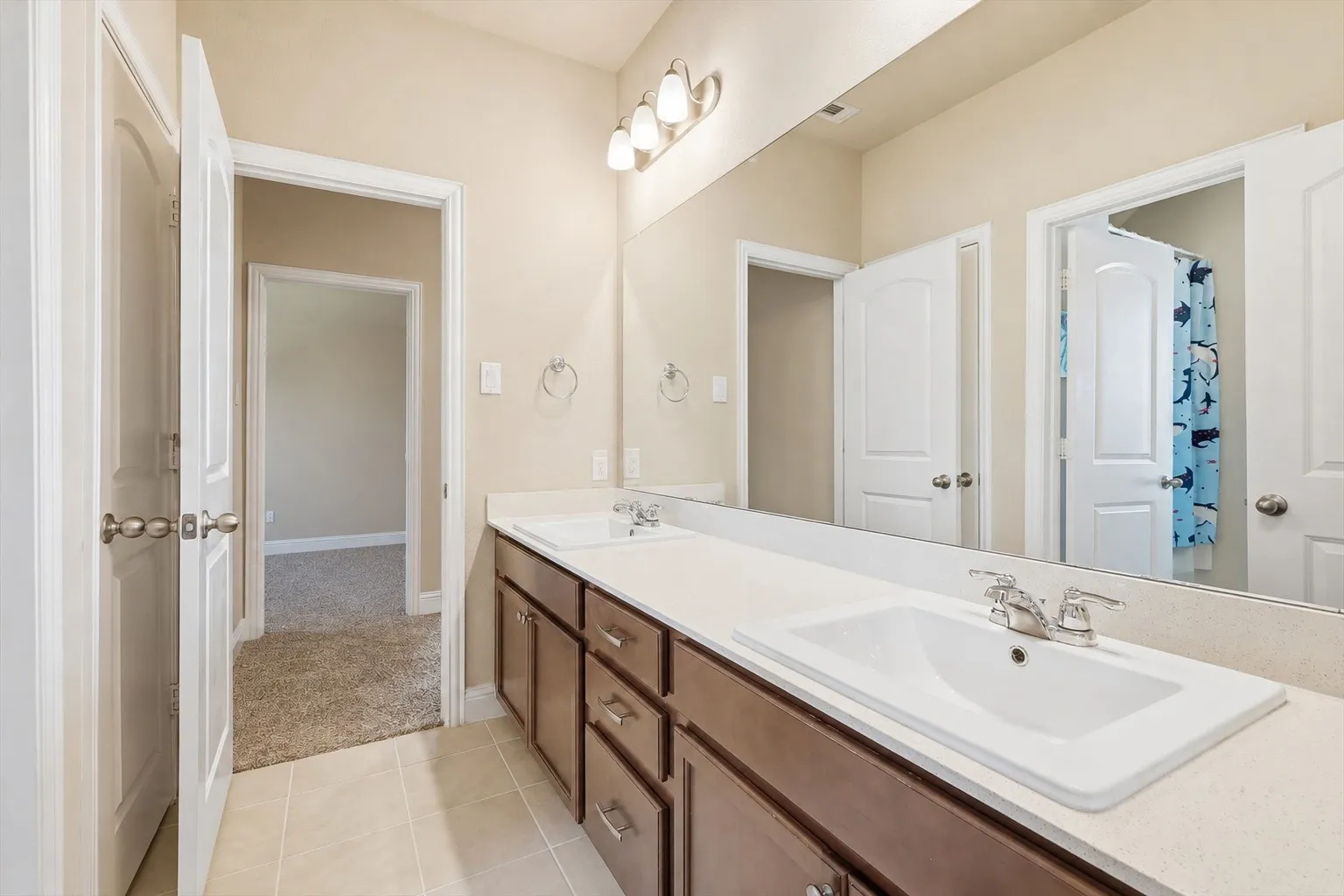 Bathroom featuring a double vanity with integrated sinks, light-toned countertop, and dark wood-finish cabinetry