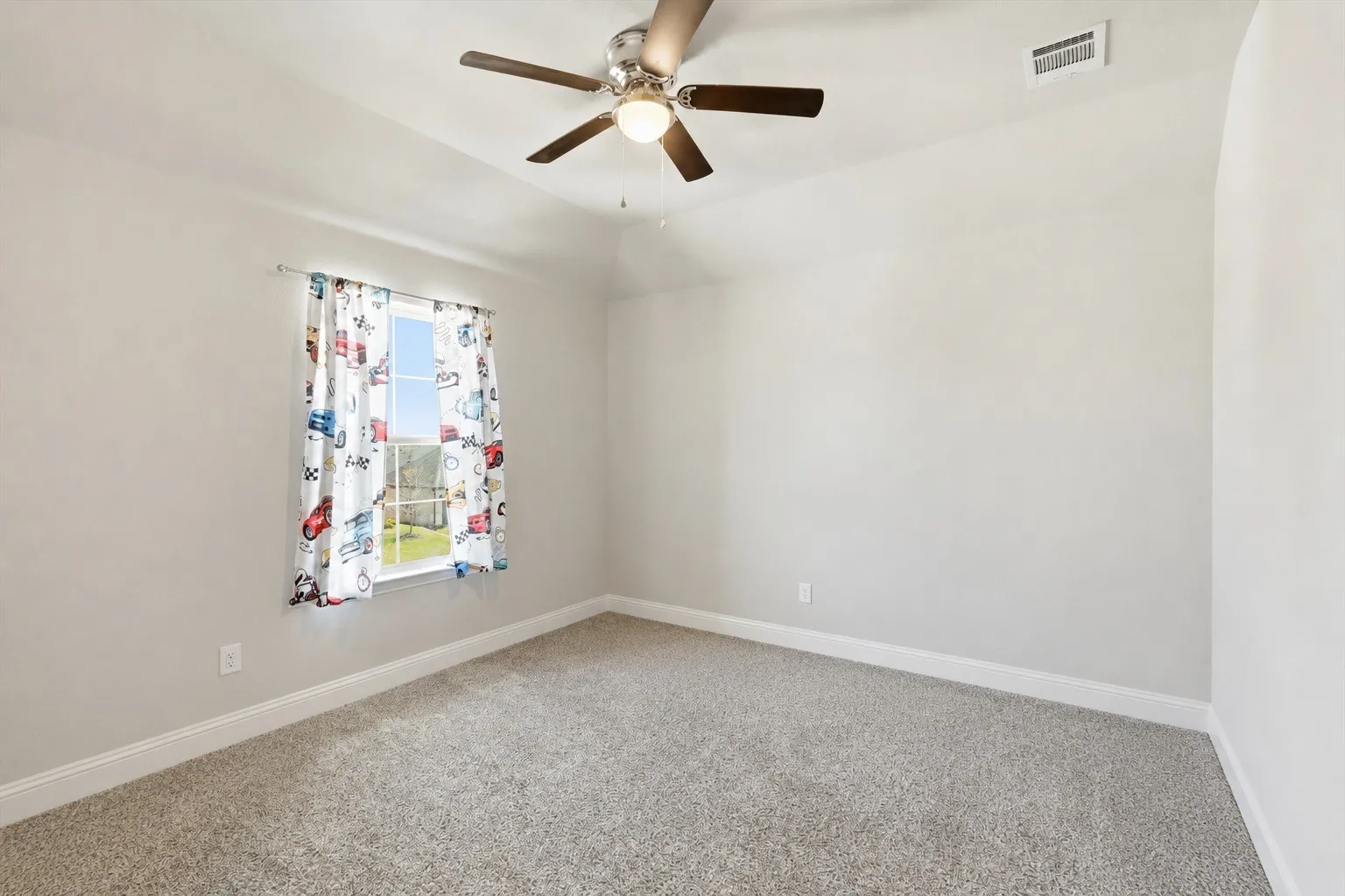 Bedroom featuring neutral carpeting, a single window, a ceiling fan with integrated lighting, and a tray ceiling