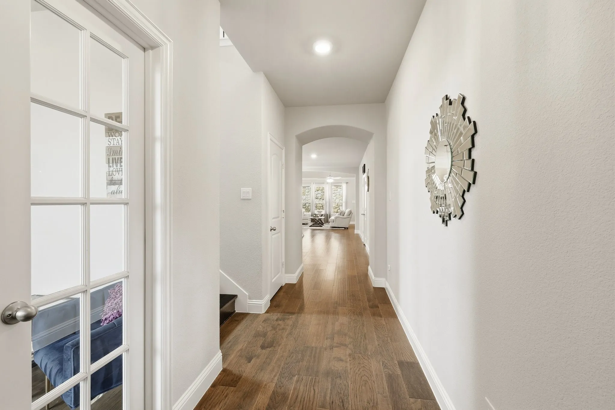 Spacious hallway featuring wood-finish flooring, recessed lighting, white trim, and an arched doorway