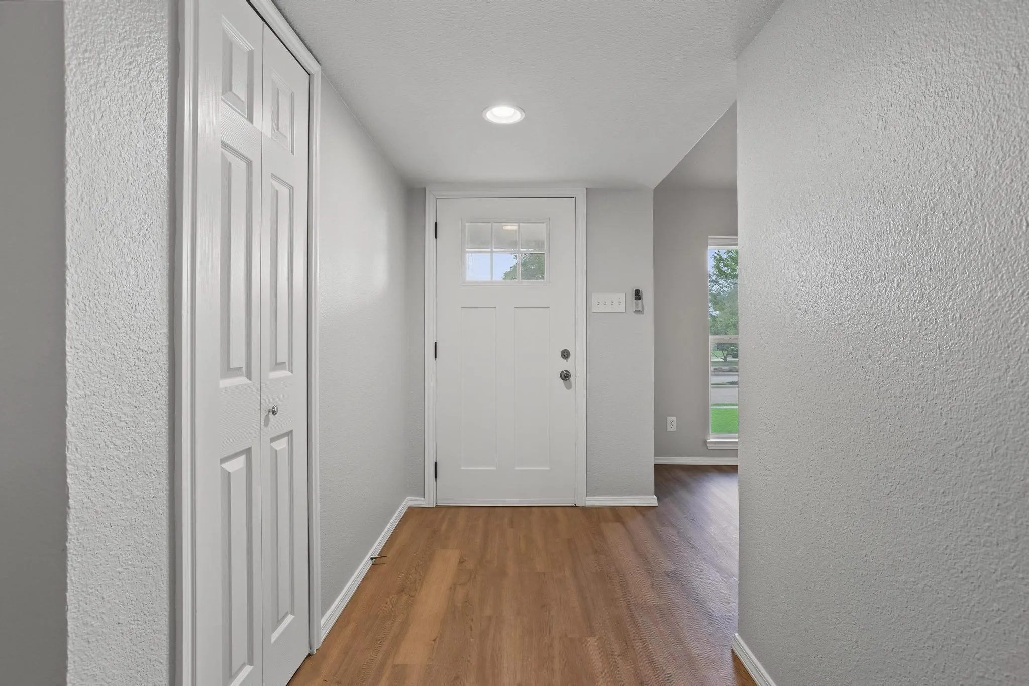 Entryway featuring wood-finish flooring, a six-panel door with glass inserts, recessed lighting, and a bi-fold closet