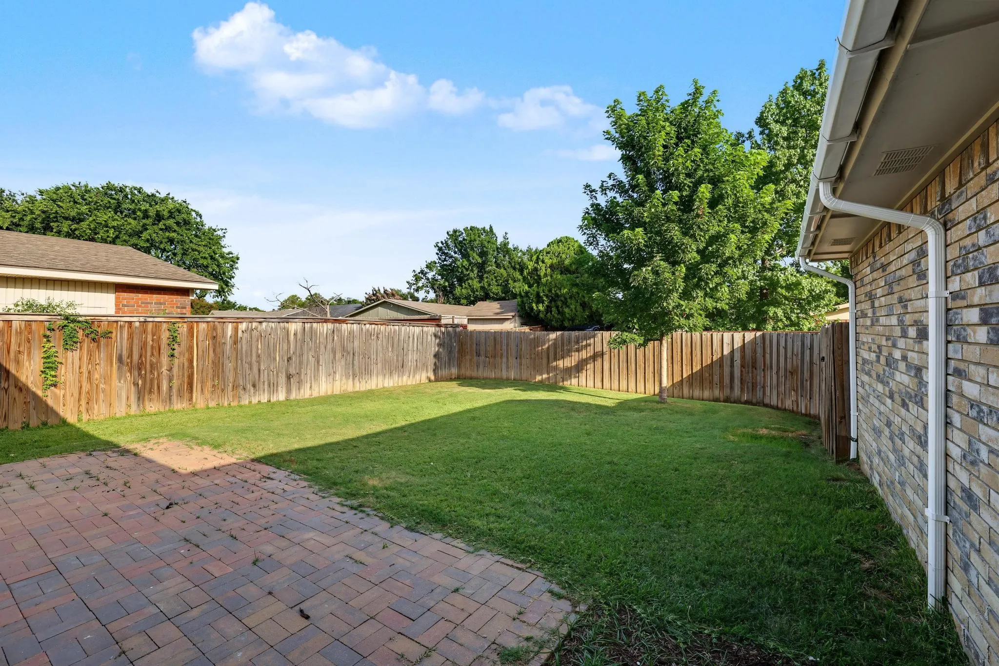 Private backyard featuring a paver patio and a surrounding wooden privacy fence