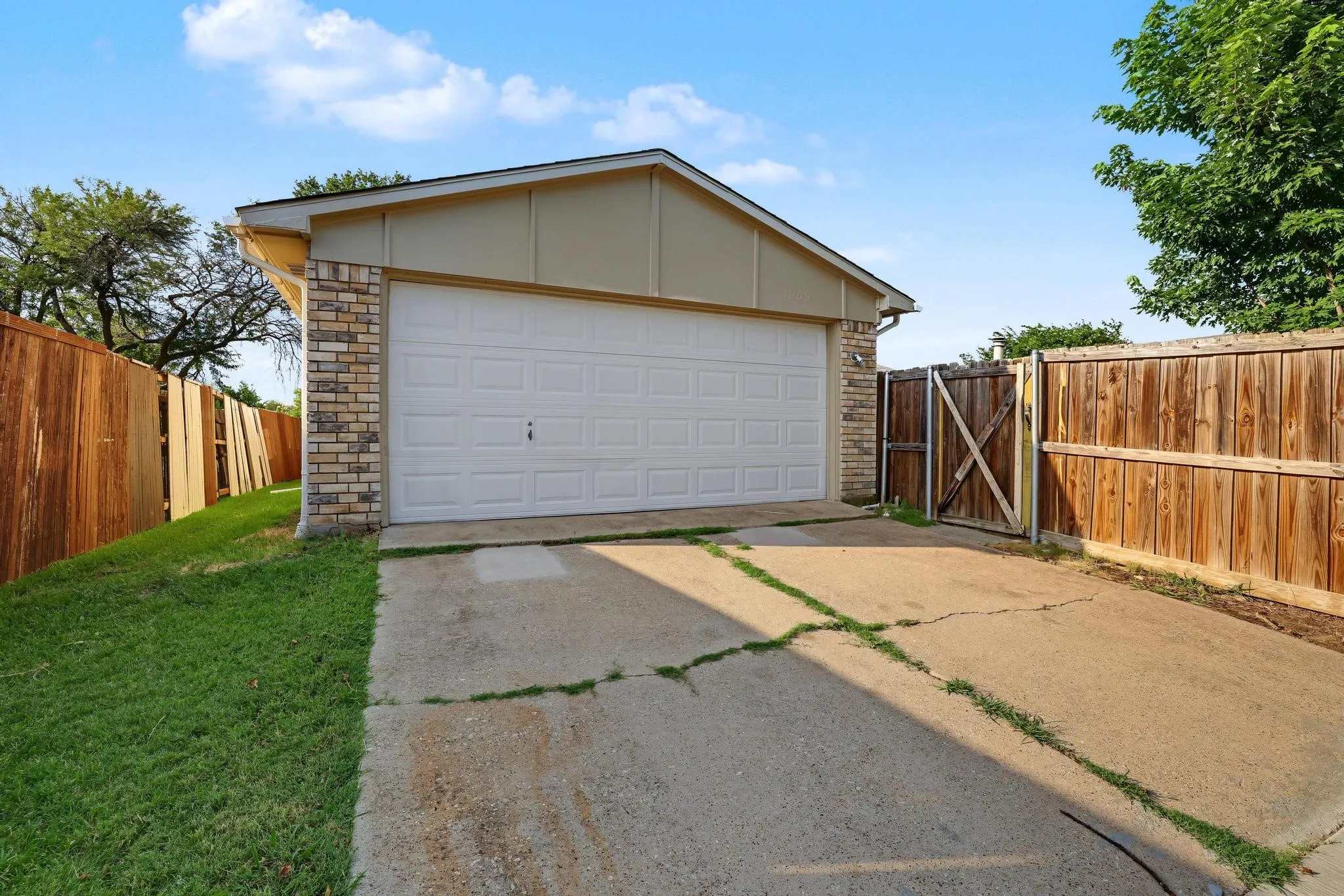Attached two-car garage with a white panel door, accented by stone veneer siding and beige fascia