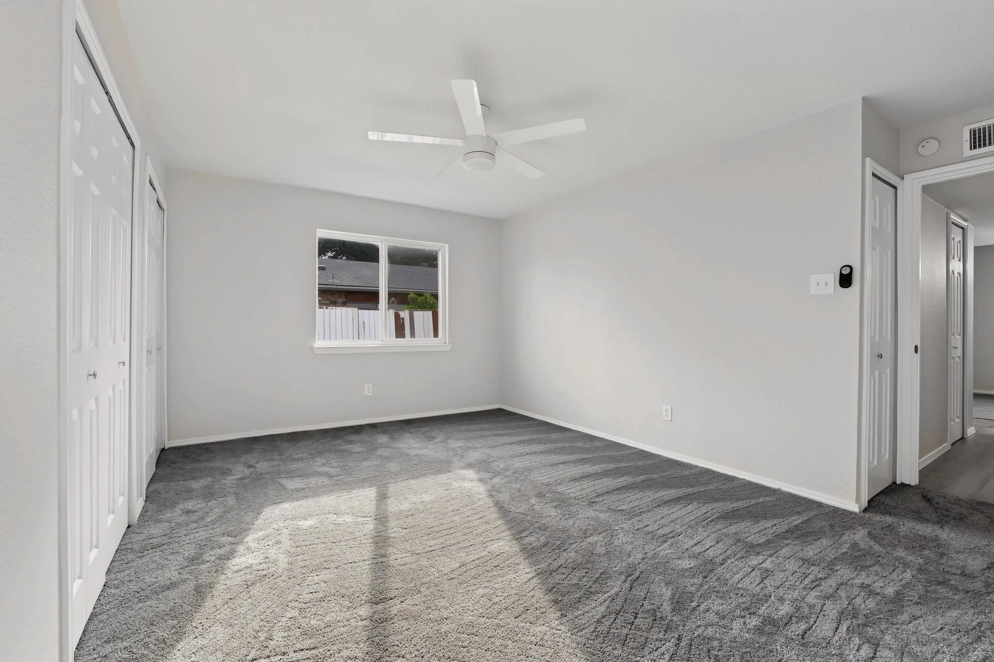 Spacious room featuring neutral grey walls and patterned grey carpeting