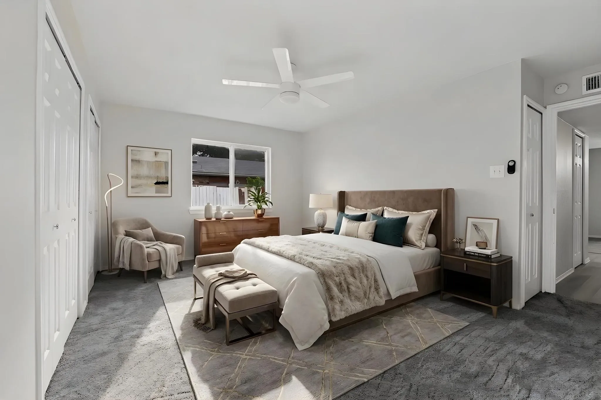 Spacious bedroom featuring light-colored walls, patterned carpeting, and a window providing natural light
