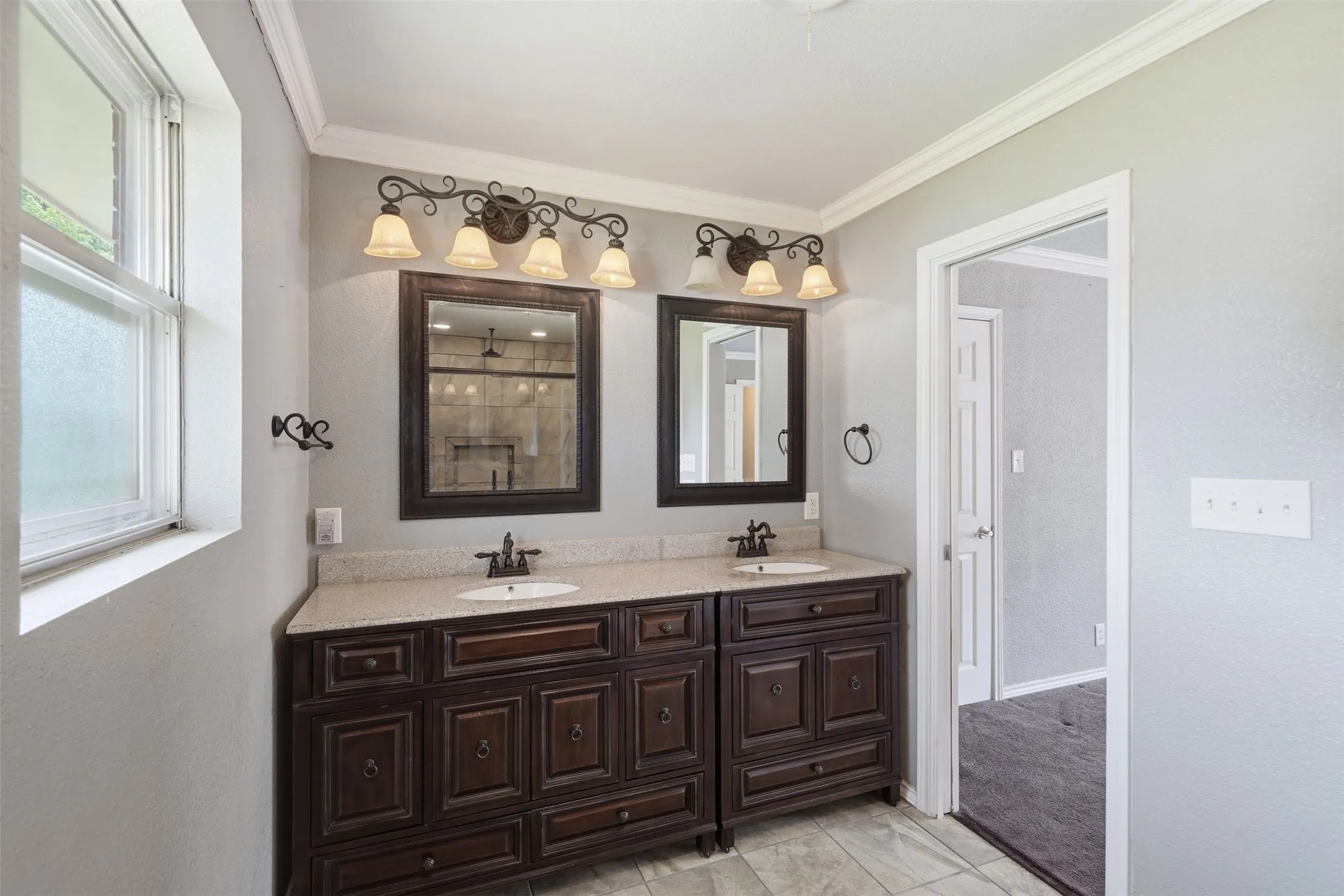 Bathroom featuring dual dark wood vanities with integrated sinks, light-toned countertops, and individual framed mirrors