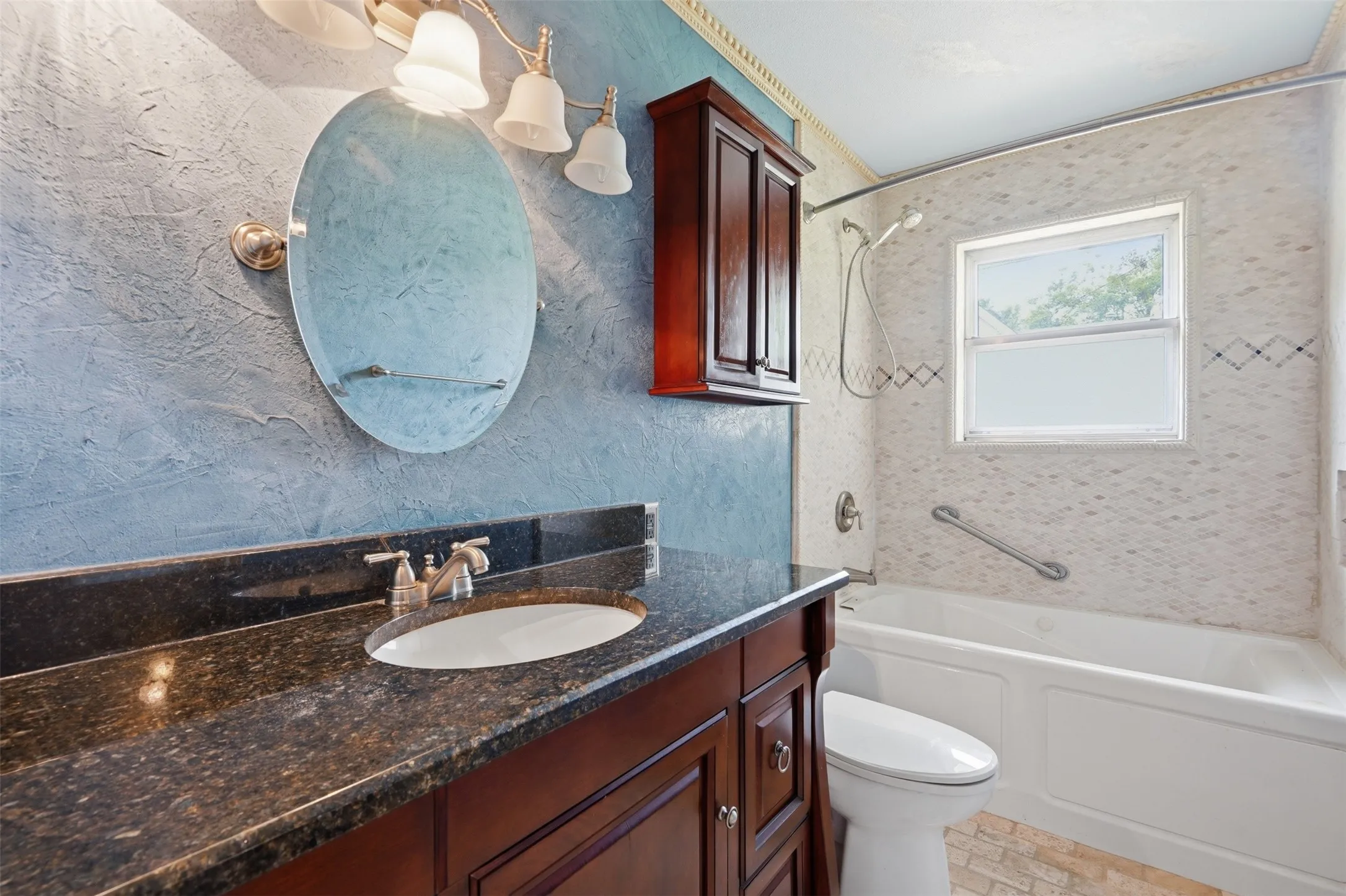 Vanity with dark countertop, undermount sink, and brushed nickel faucet