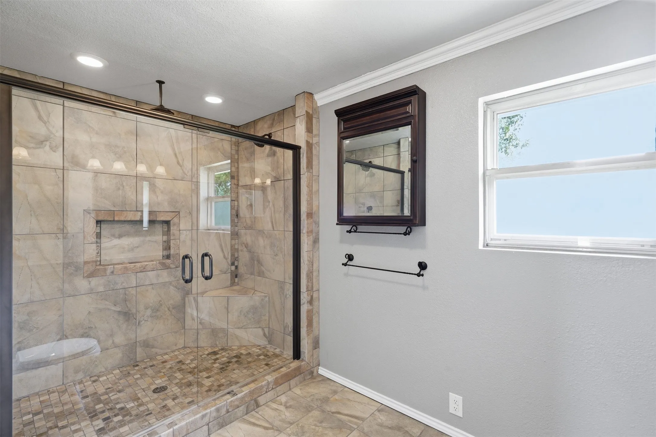 Spacious walk-in shower with clear glass enclosure and dark bronze framing