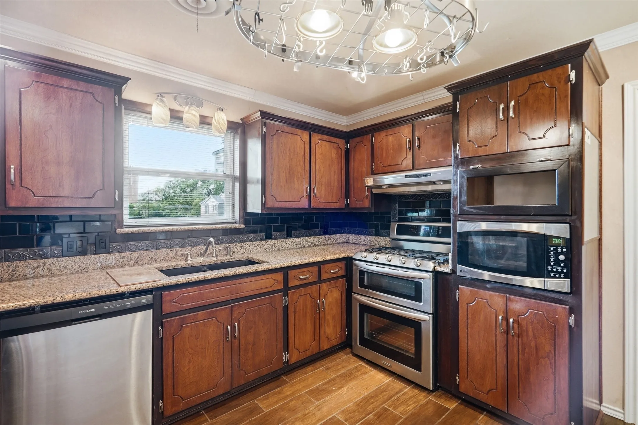 Kitchen featuring wood cabinetry, a double basin sink, stainless steel appliances, and wood-finish flooring