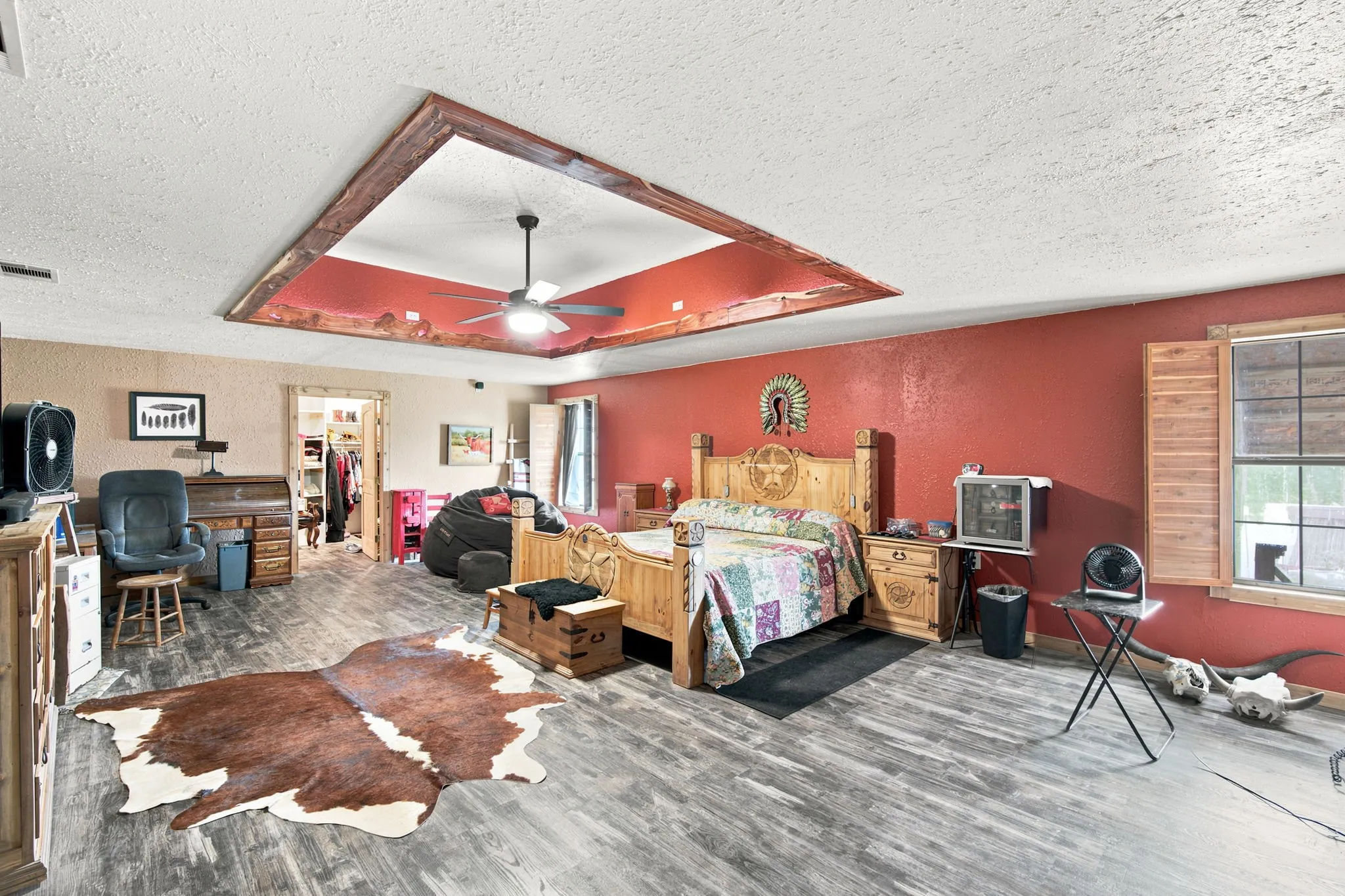 Huge 28' X 18' Primary bedroom features ceiling treatment with ceiling fan and shutters for windows.