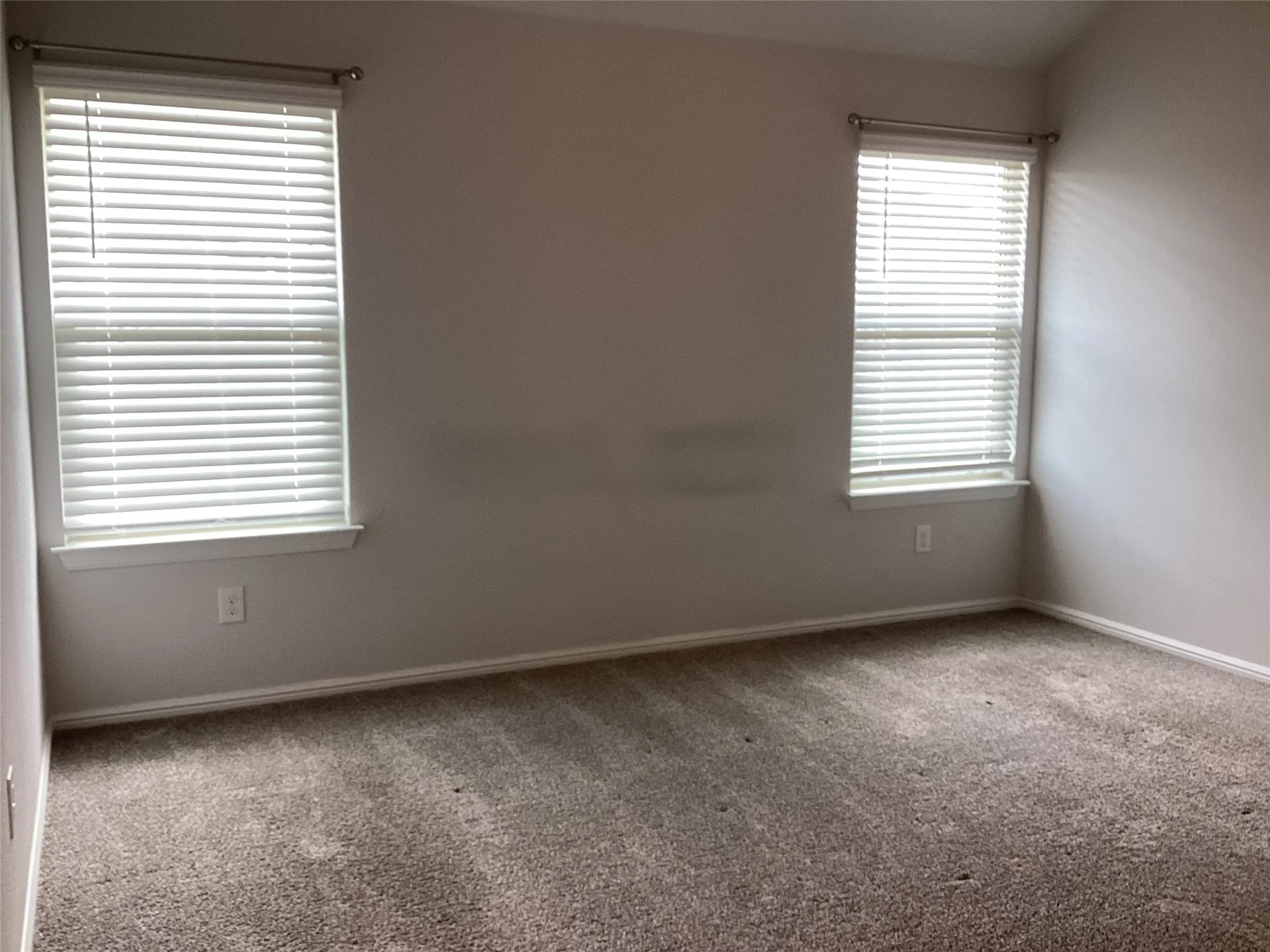 Carpeted room with two windows featuring horizontal blinds