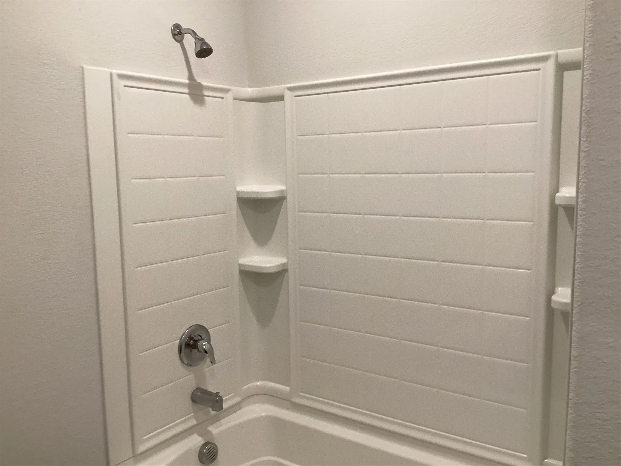 White tub and shower combination with chrome fixtures
