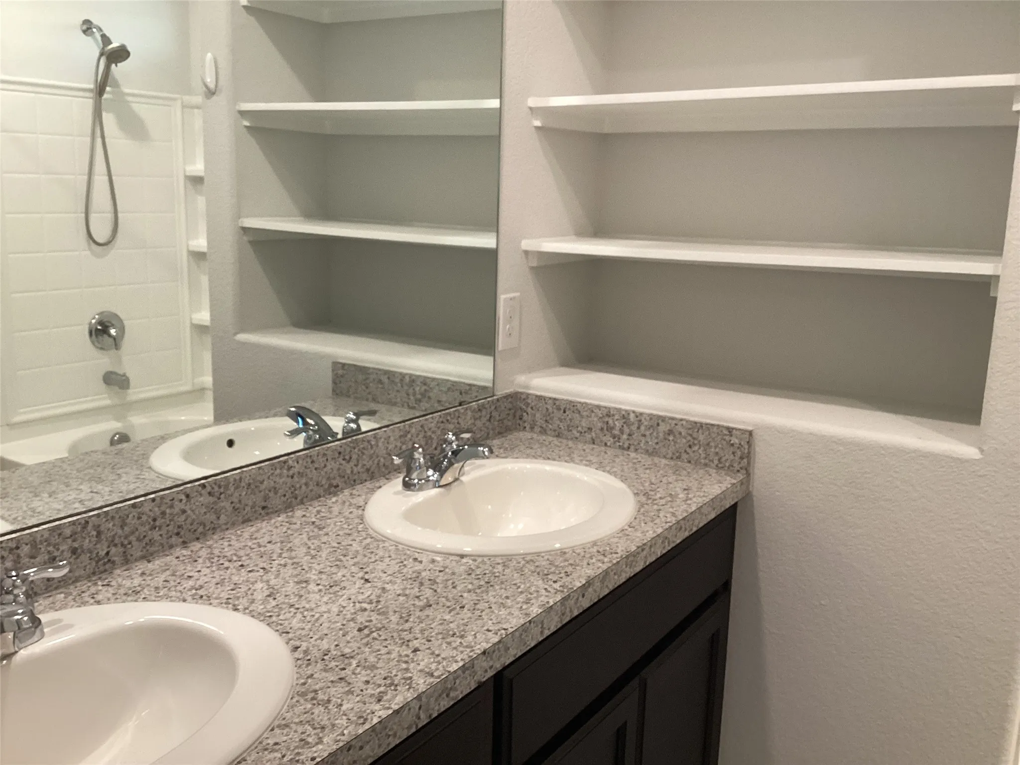 Dual vanity featuring integrated sinks, chrome fixtures, and a speckled countertop