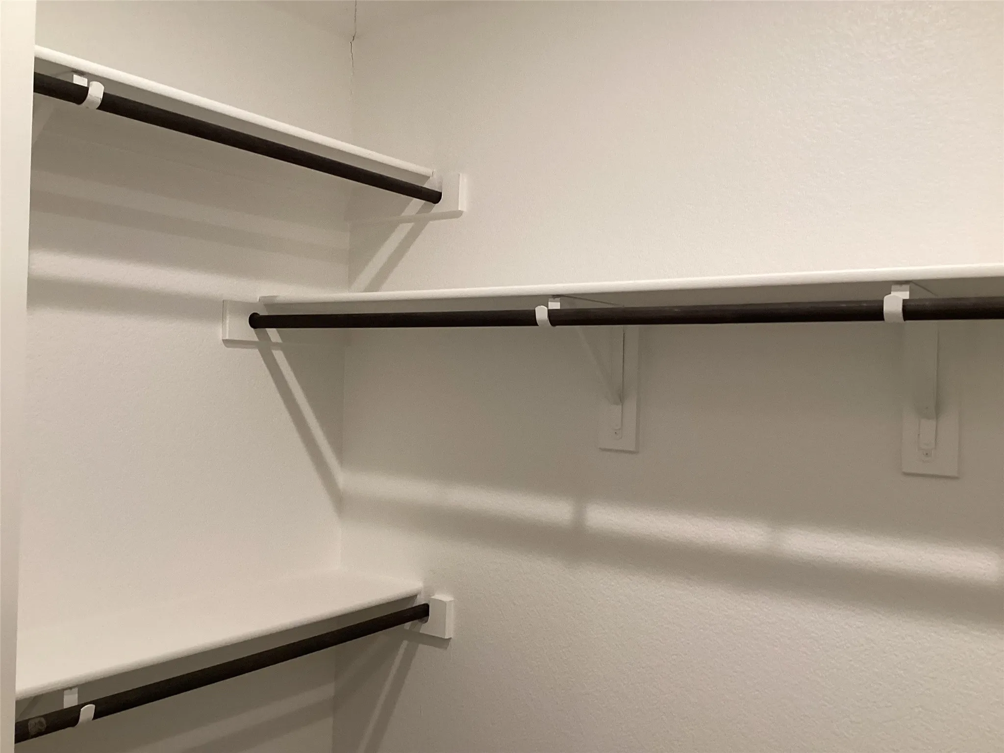 Built-in closet system featuring white shelving and dark-toned hanging rods