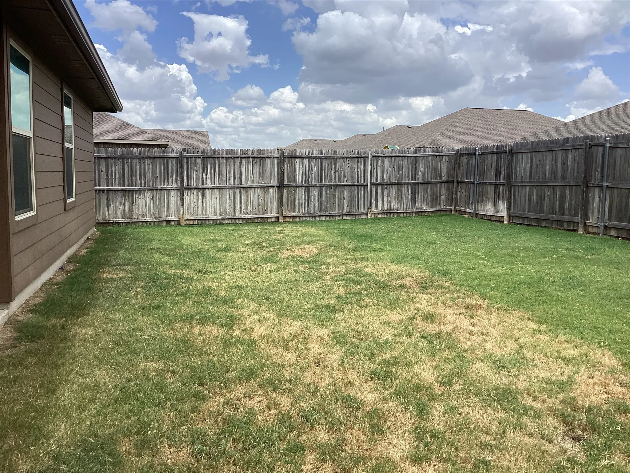 Spacious grass lawn enclosed by a wood privacy fence