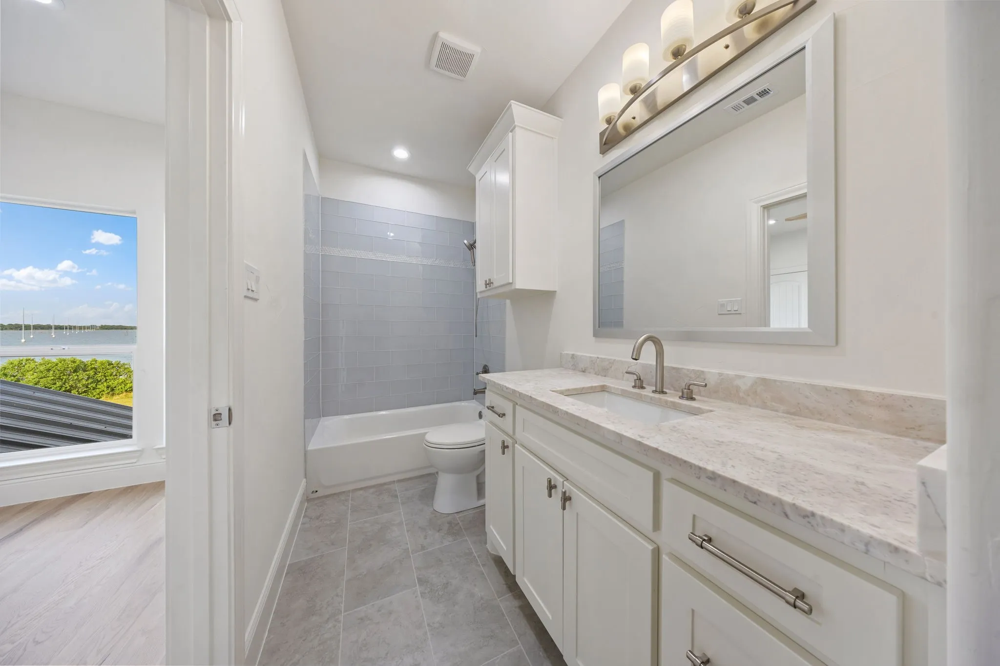 Bathroom featuring a single vanity with stone countertop, white cabinetry, and brushed nickel hardware
