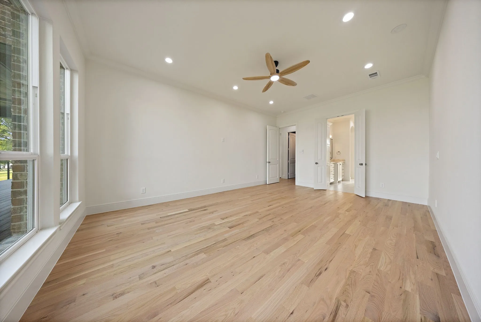 Spacious room featuring wood-finish flooring, recessed lighting, and a ceiling fan