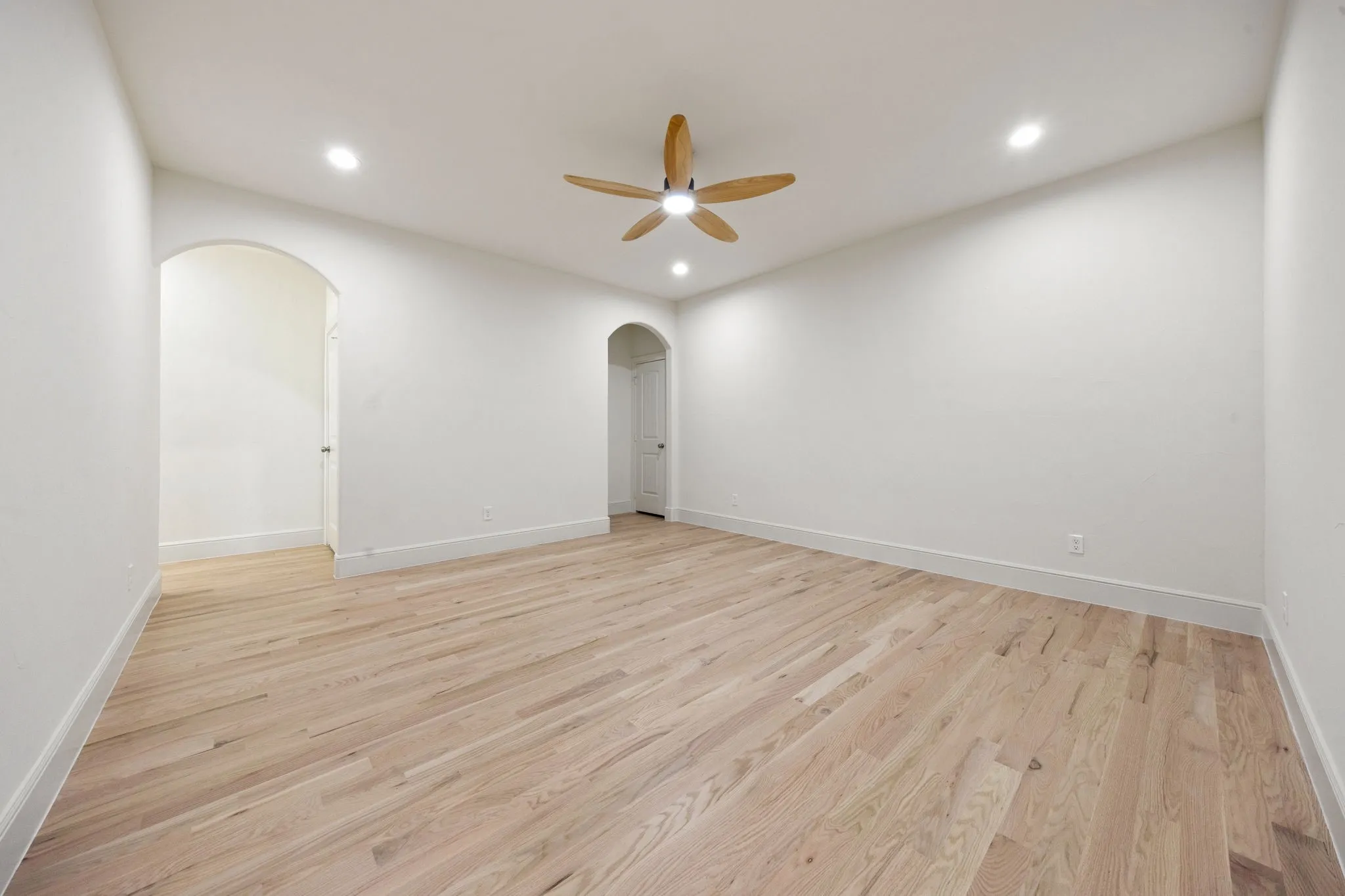 Spacious room featuring light wood-finish flooring, recessed lighting, and a ceiling fan