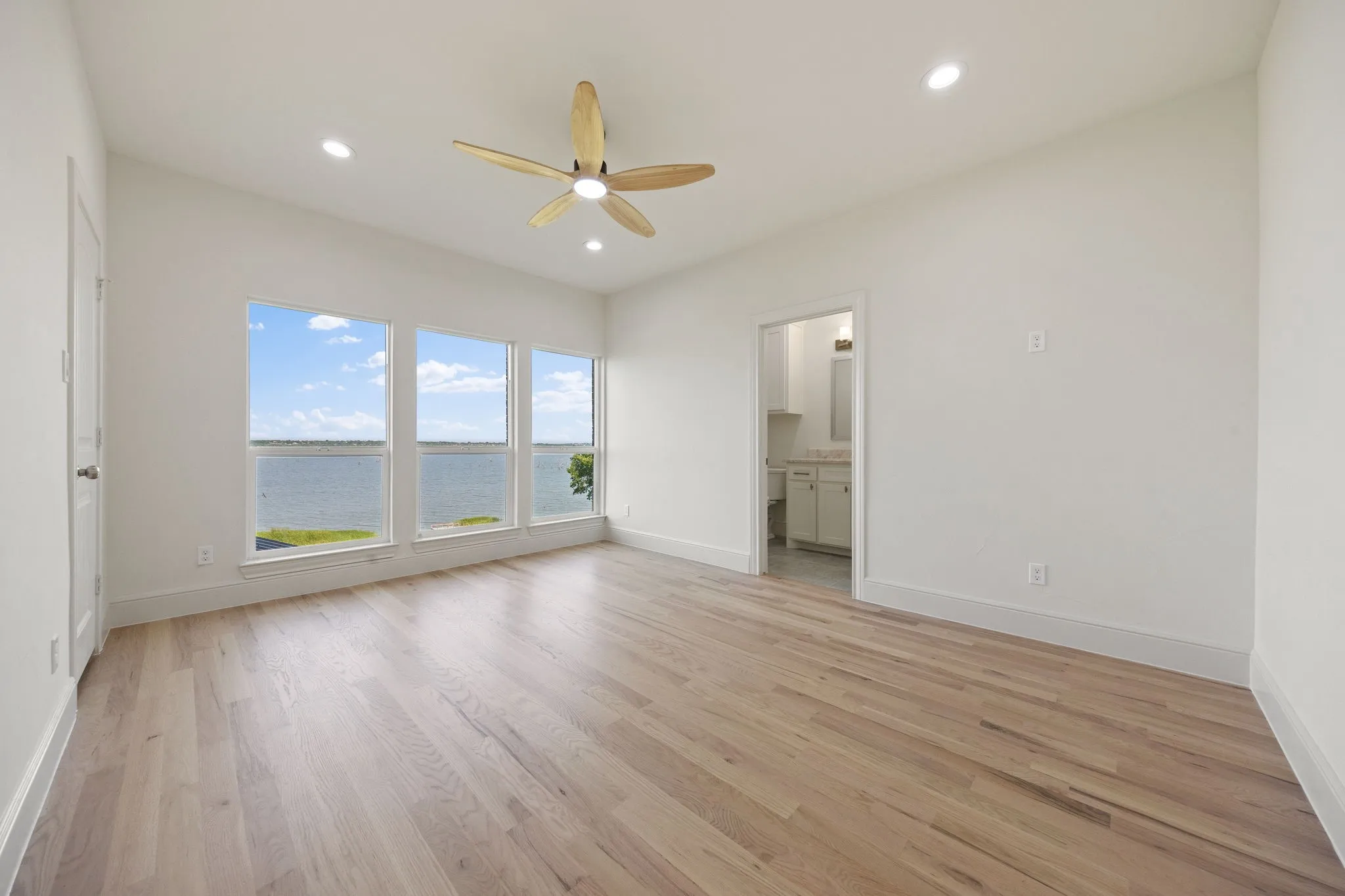 Expansive room featuring three large windows showcasing a water backdrop