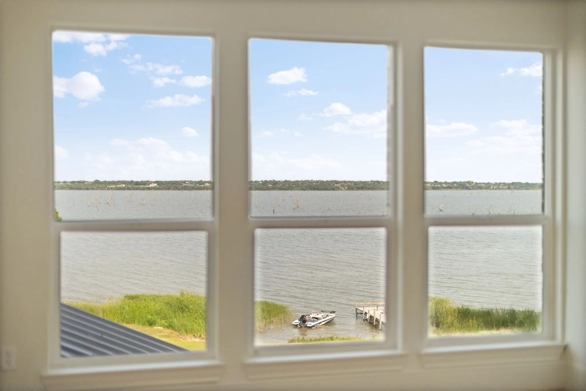 Multiple white-framed windows framing expansive water scenery with distant land
