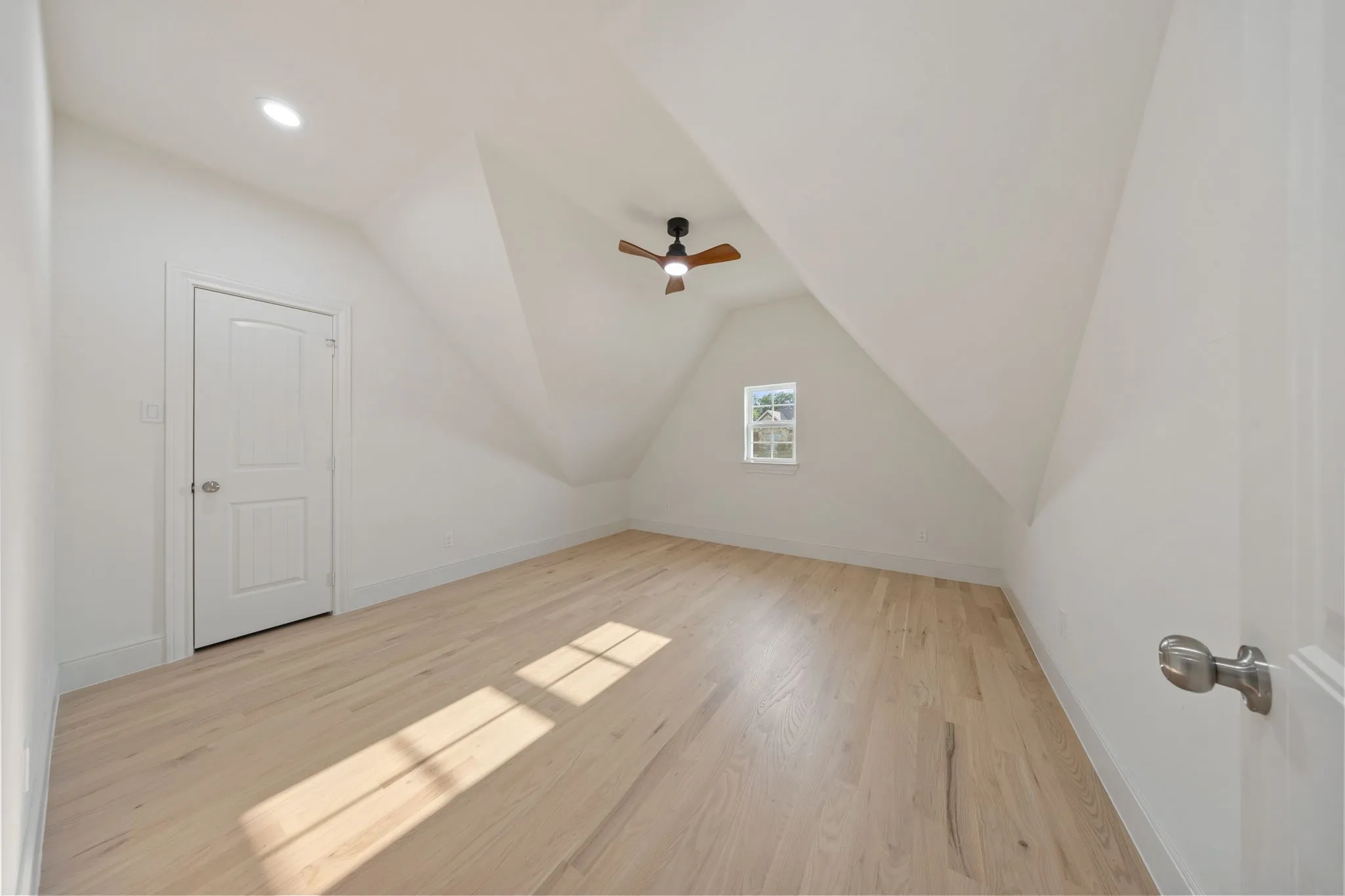 Spacious room featuring wood-finish flooring, a ceiling fan, recessed lighting, and a white-framed window