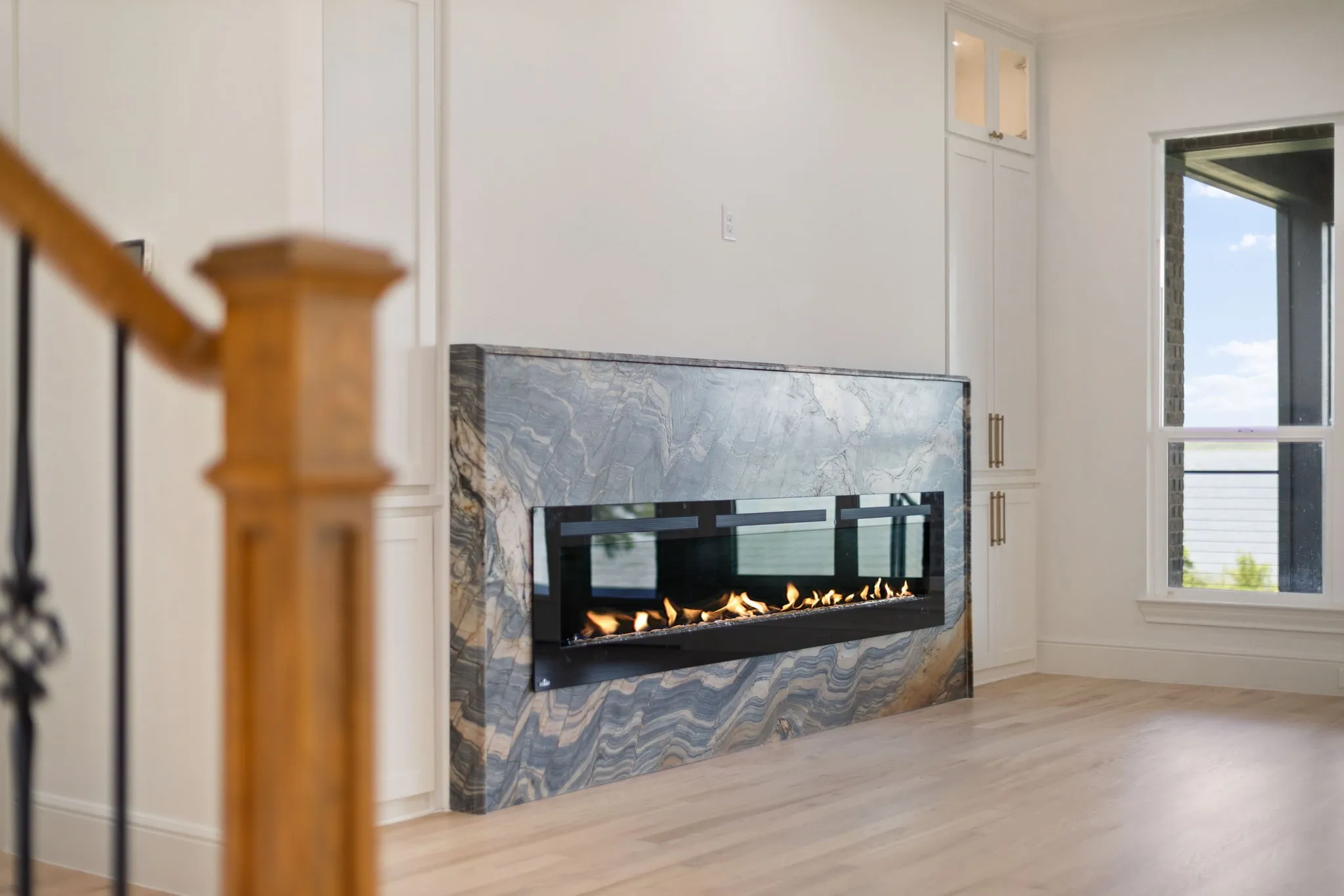 Modern linear fireplace featuring a stone surround with black and gray veining