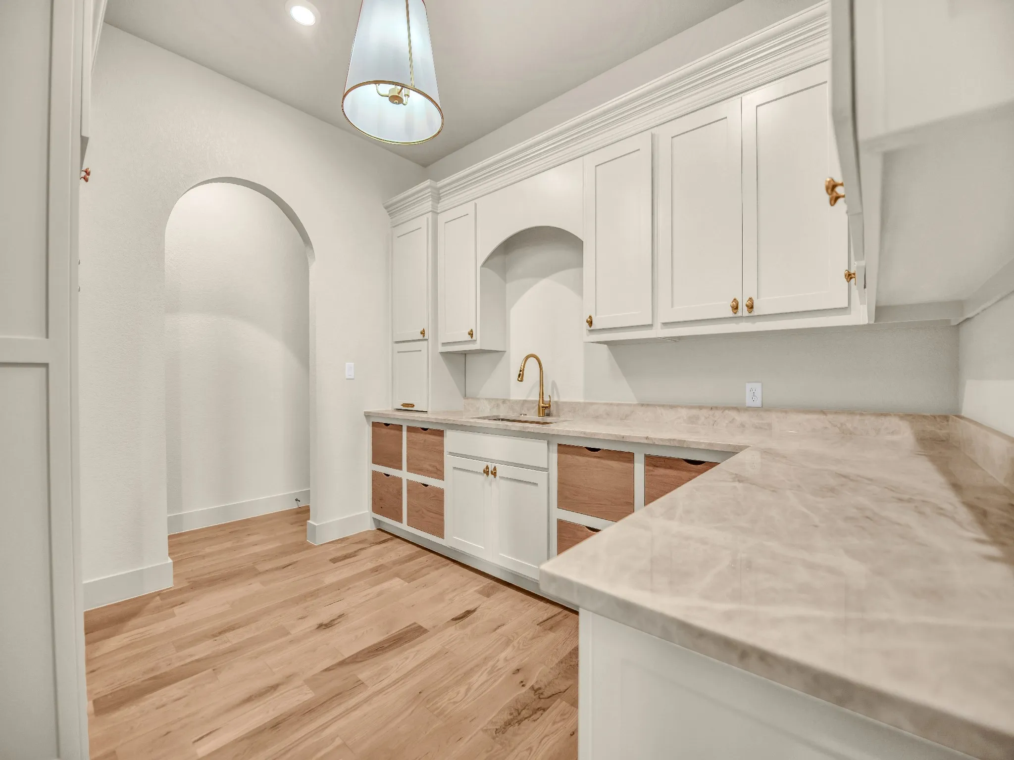 Built-in cabinetry with crown molding, light-toned countertops, and wood-finish flooring