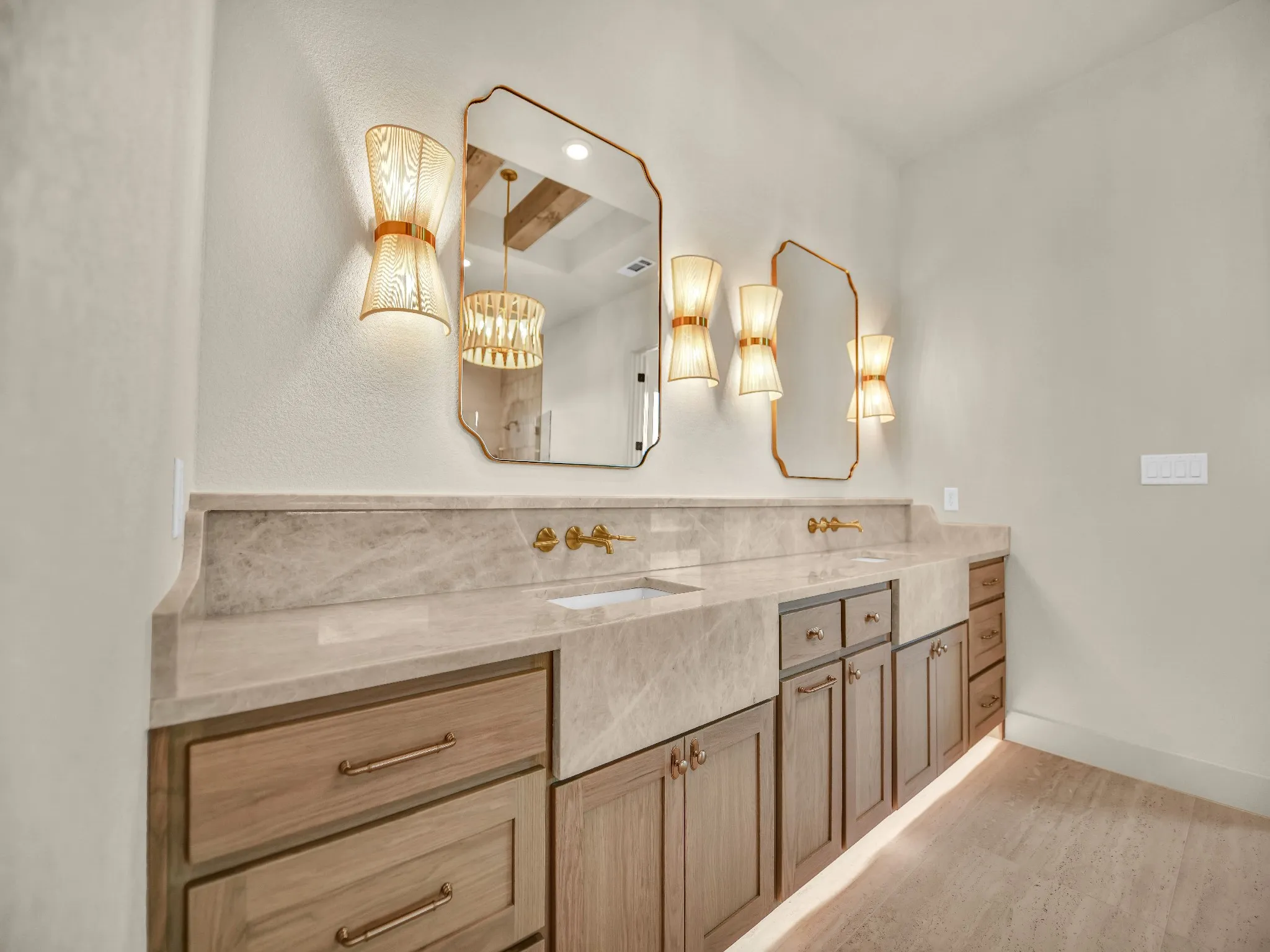 Double vanity with under-cabinet lighting, integrated sinks, a marble-finish countertop, and gold-finish fixtures
