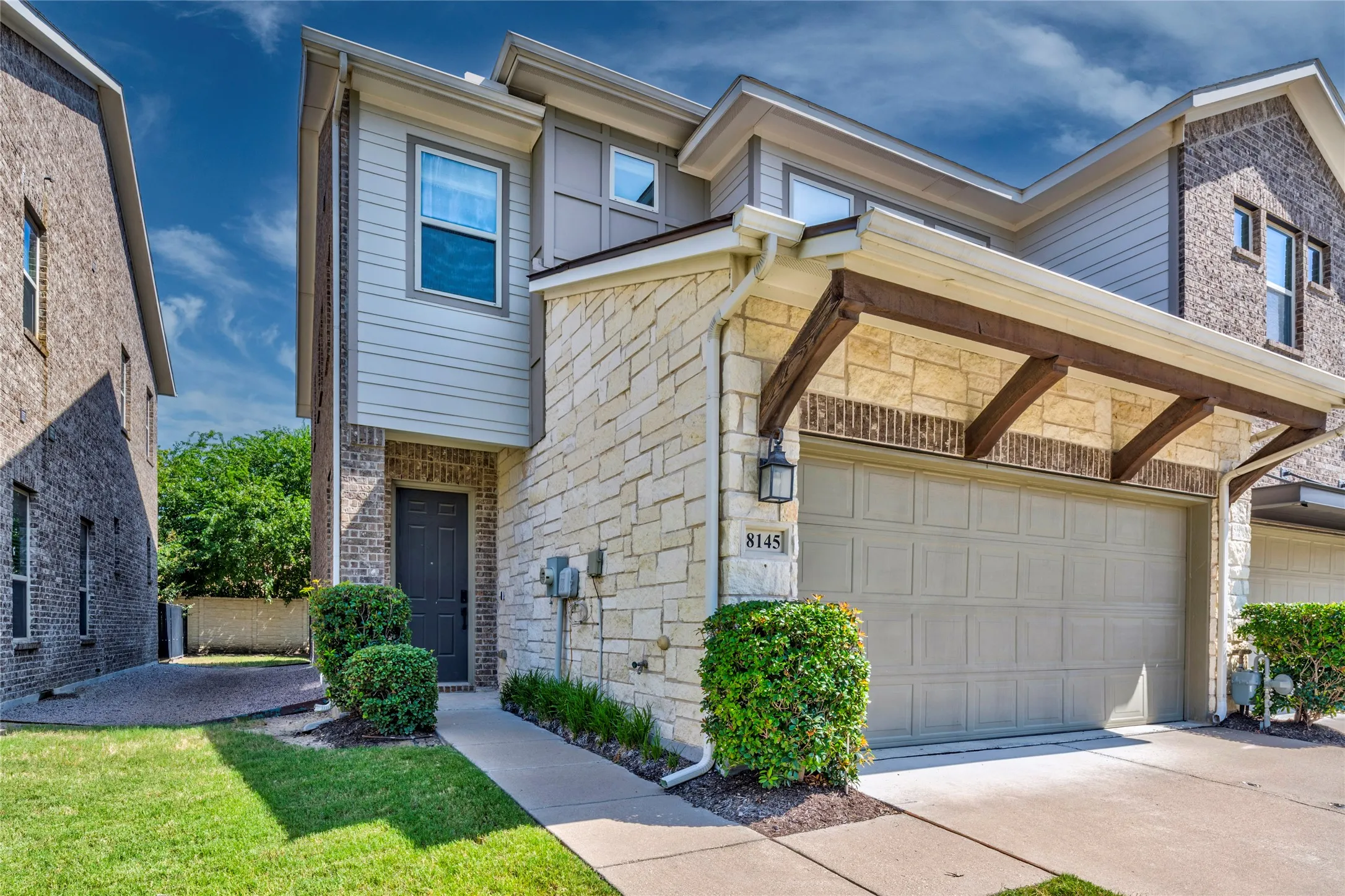 Contemporary exterior featuring stone veneer, brick accents, and horizontal siding