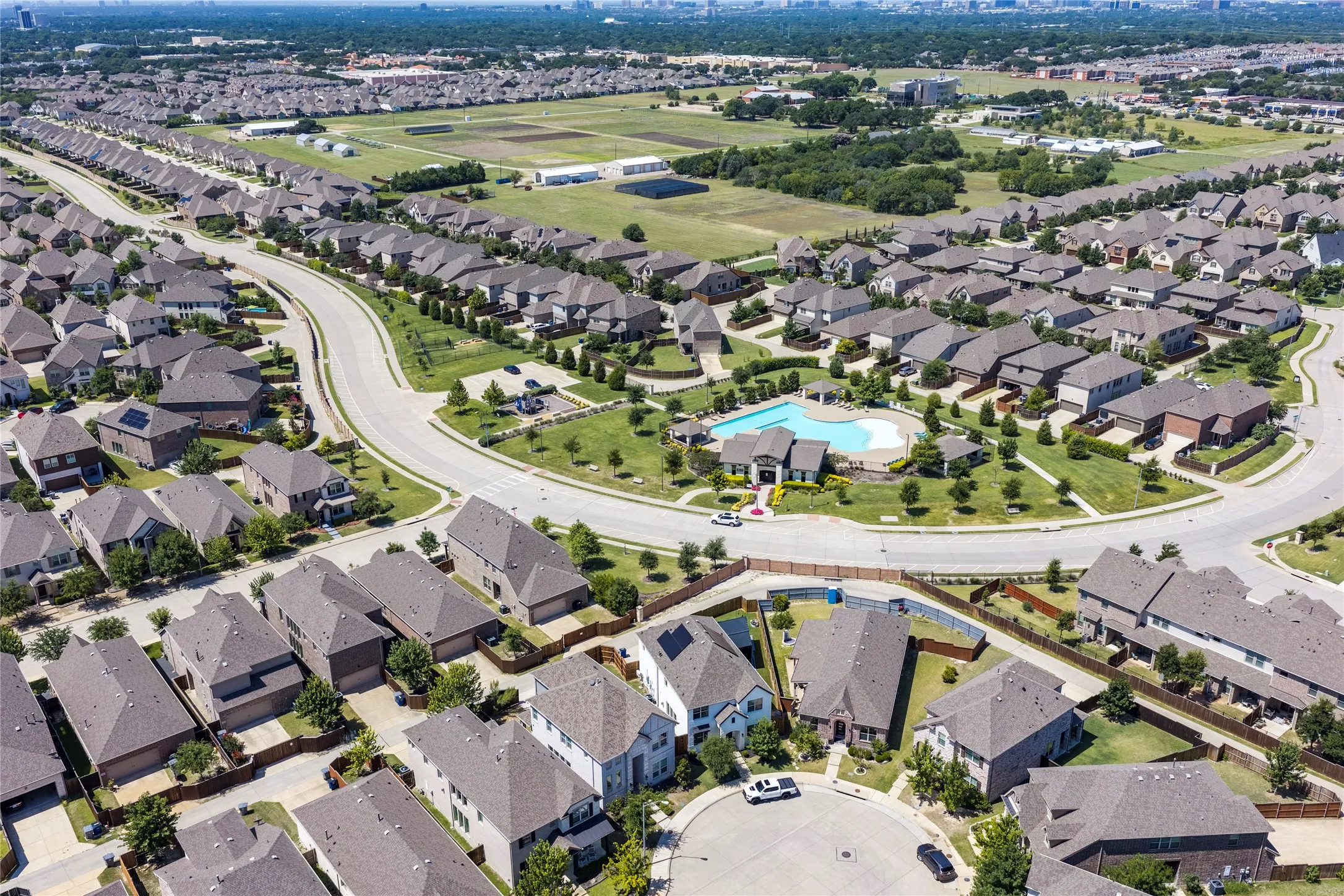 Aerial perspective of a residential community featuring a curvilinear street layout and a central amenity area