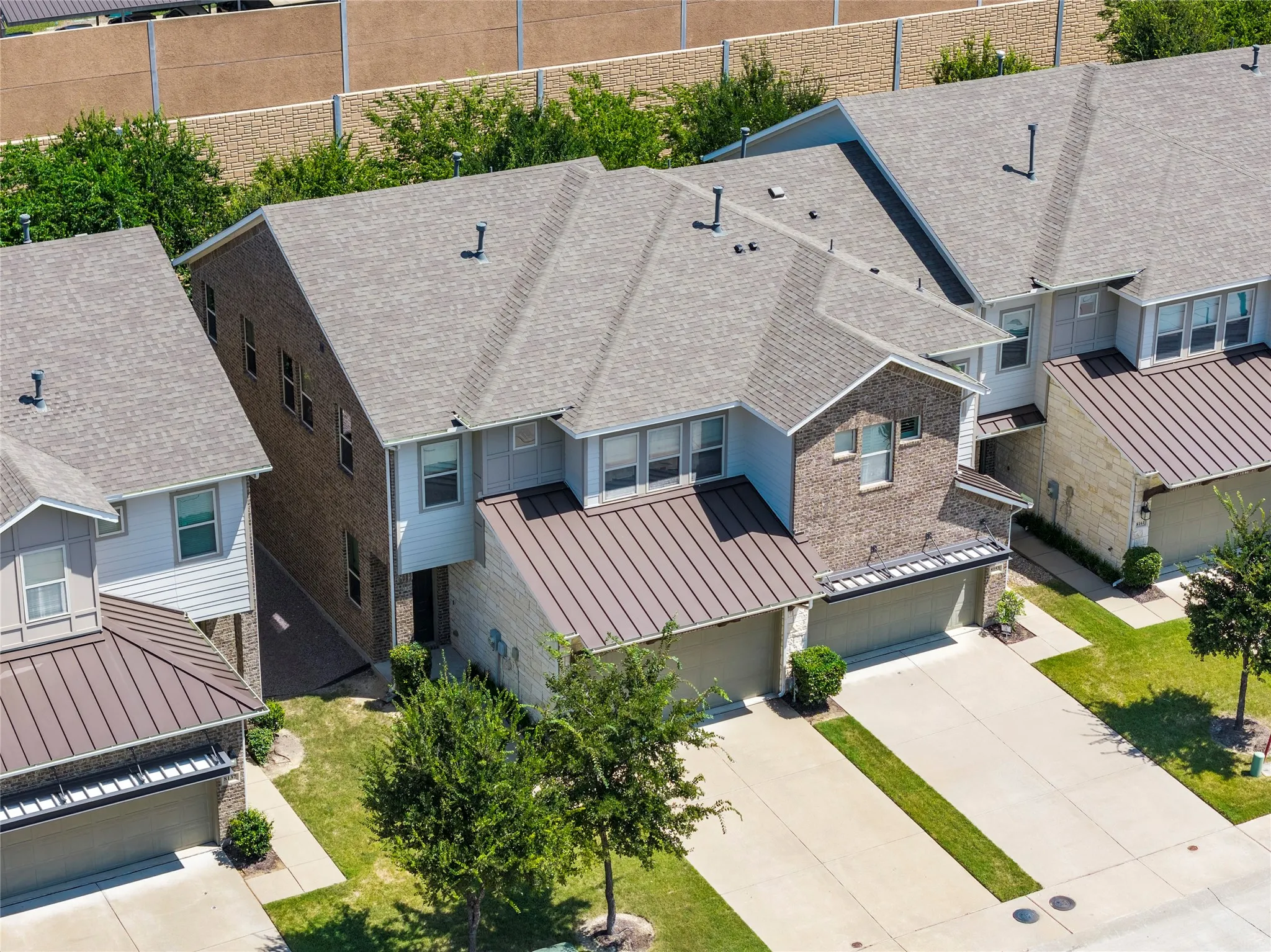 Contemporary multi-story residence featuring a brick and siding facade, an attached two-car garage with a brown metal roof accent, and a light gray shingle roof